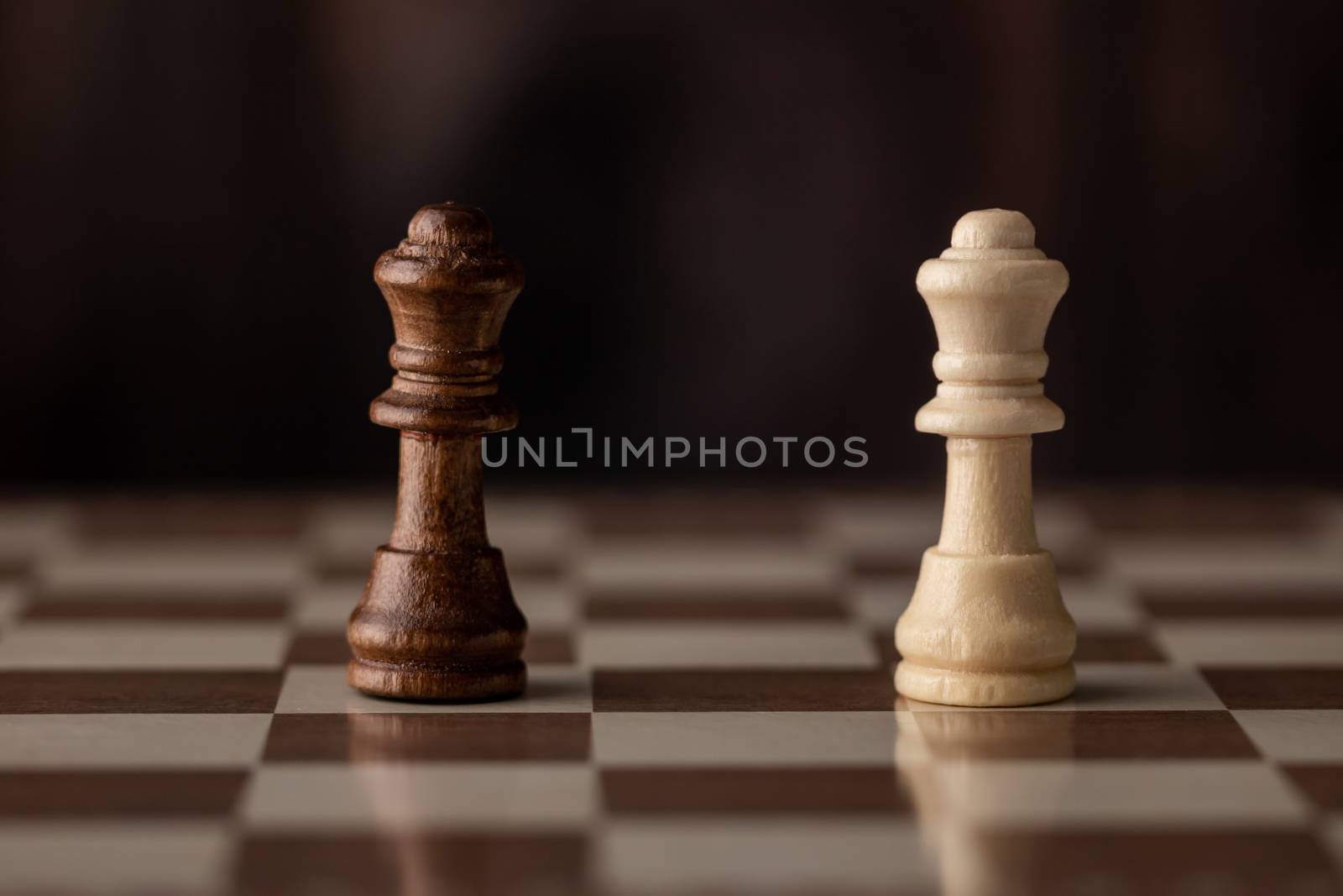 Queens on the chessboard and wooden background