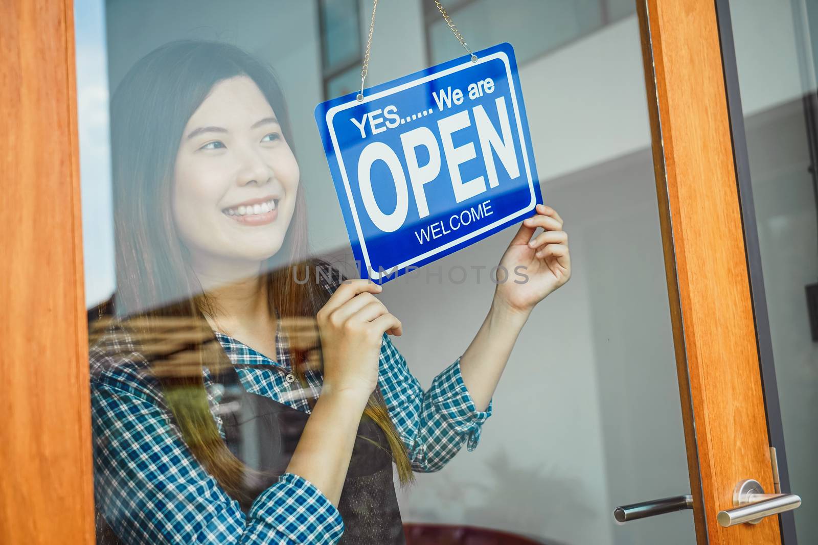 Closeup hand of Asian young woman setting open sign at the shop glasses for welcome the customer in to the coffee shop, small business owner and startup, installing open and close label concept