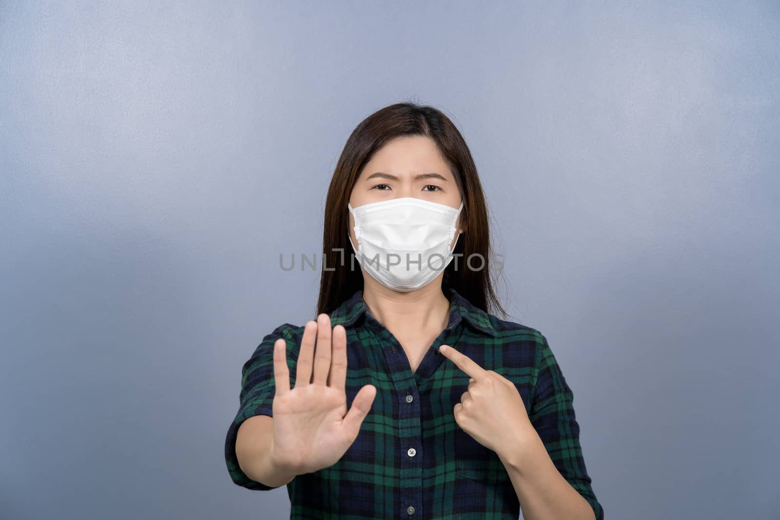 Portrait of asian female wearing face surgical mask and say no action to coronavirus  infection on blue color background, covid19 outbreak and pandemic, healthcare and protection against virus concept
