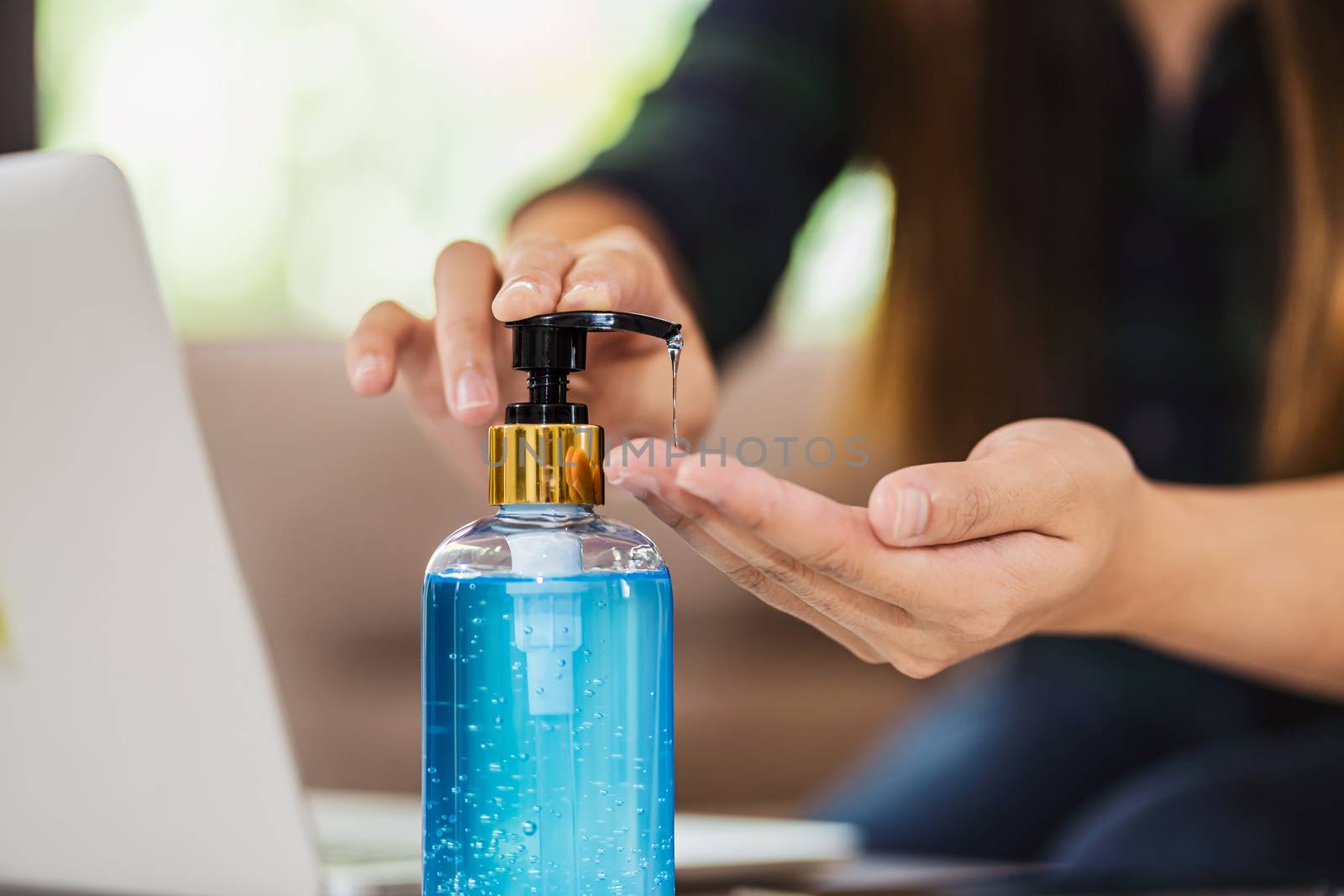 Closeup Asian female using hand sanitizer by pumping alcohol gel and washing before working with laptop in work from home period,coronavirus or covid19 outbreak,social distancing and responsibility