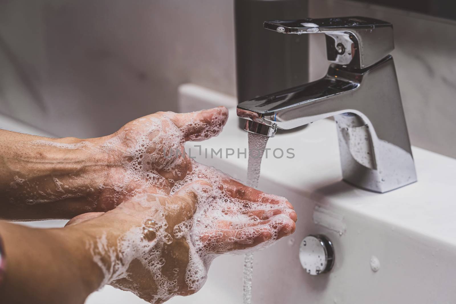 Closeup hands washing with Chrome faucet and soap for Coronavirus pandemic prevention in bathroom, self responsibility cleaning, hand hygiene corona virus protection concept