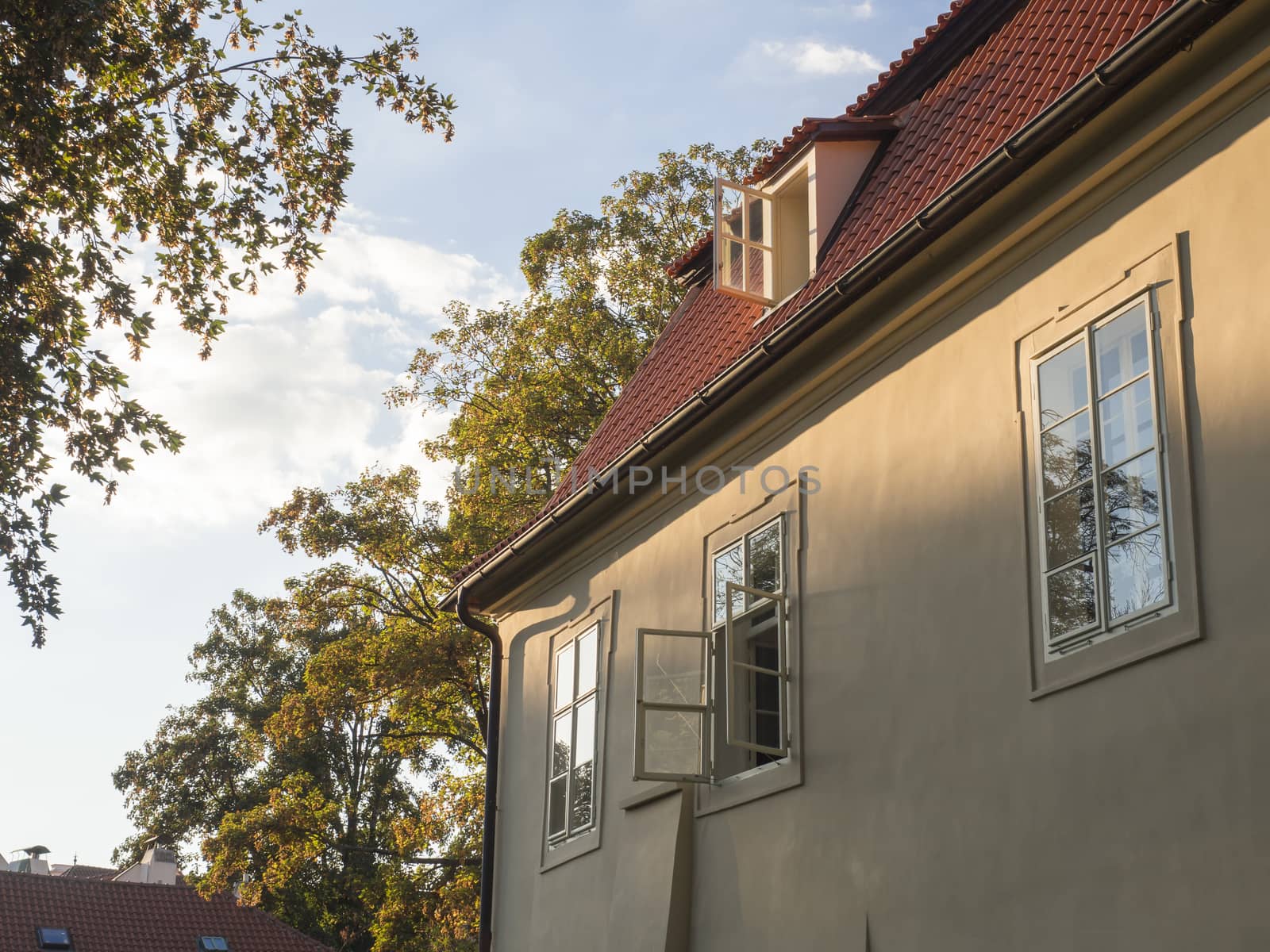 old prague baroque house at Kampa with open window in golden hour light, trees and sky background.