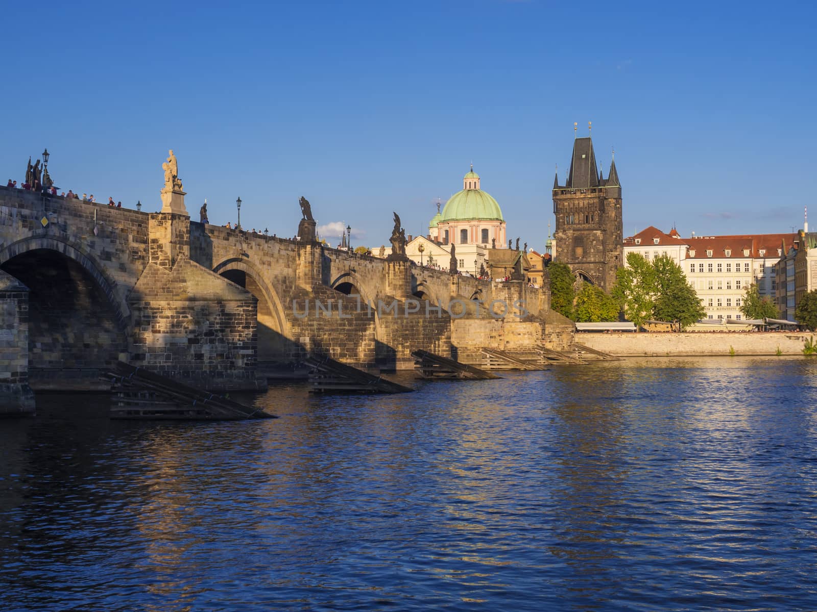 View of Charles Bridge in Prague from Kampa, Czech Republic. Gothic Charles Bridge is one of the most visited sights in Prague. Architecture and landmark of Prague, golden light, sunny summer day.