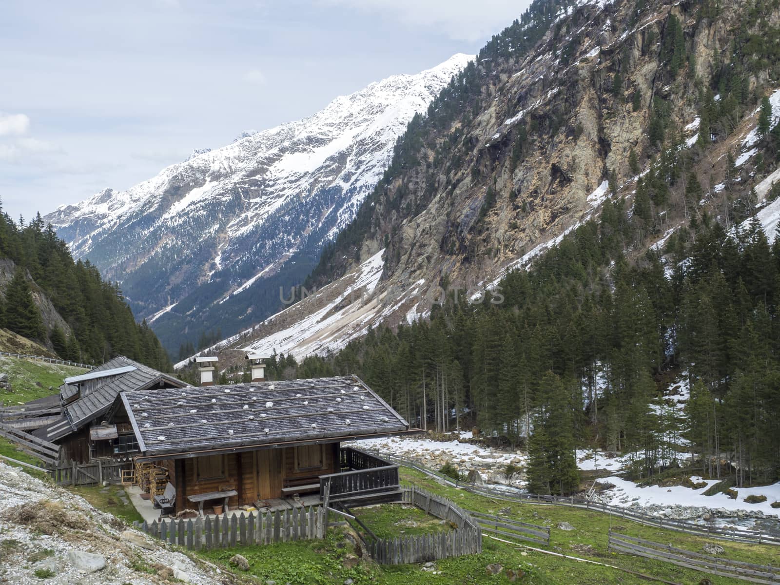 Alpine wooden cottage near GRAWA Glacier Waterfall situated in Stubai Valley, Tyrol, Austria. Spring mountain river and trees landscape natural environment. Hiking in the alps