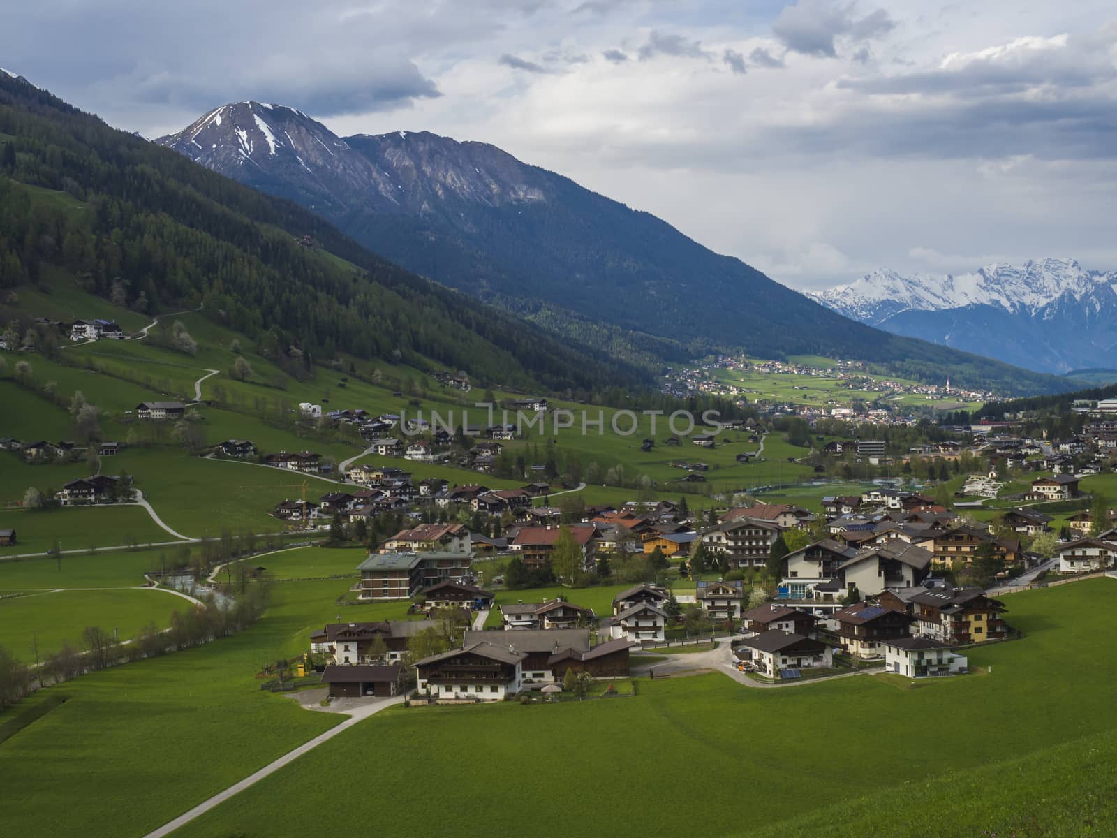 Idyllic spring mountain rural landscape. View over Stubaital or Stubai Valley near Innsbruck, Austria with village Neder and Neustift im Stubaital, green meadow, snow covered alpen mountain peaks.