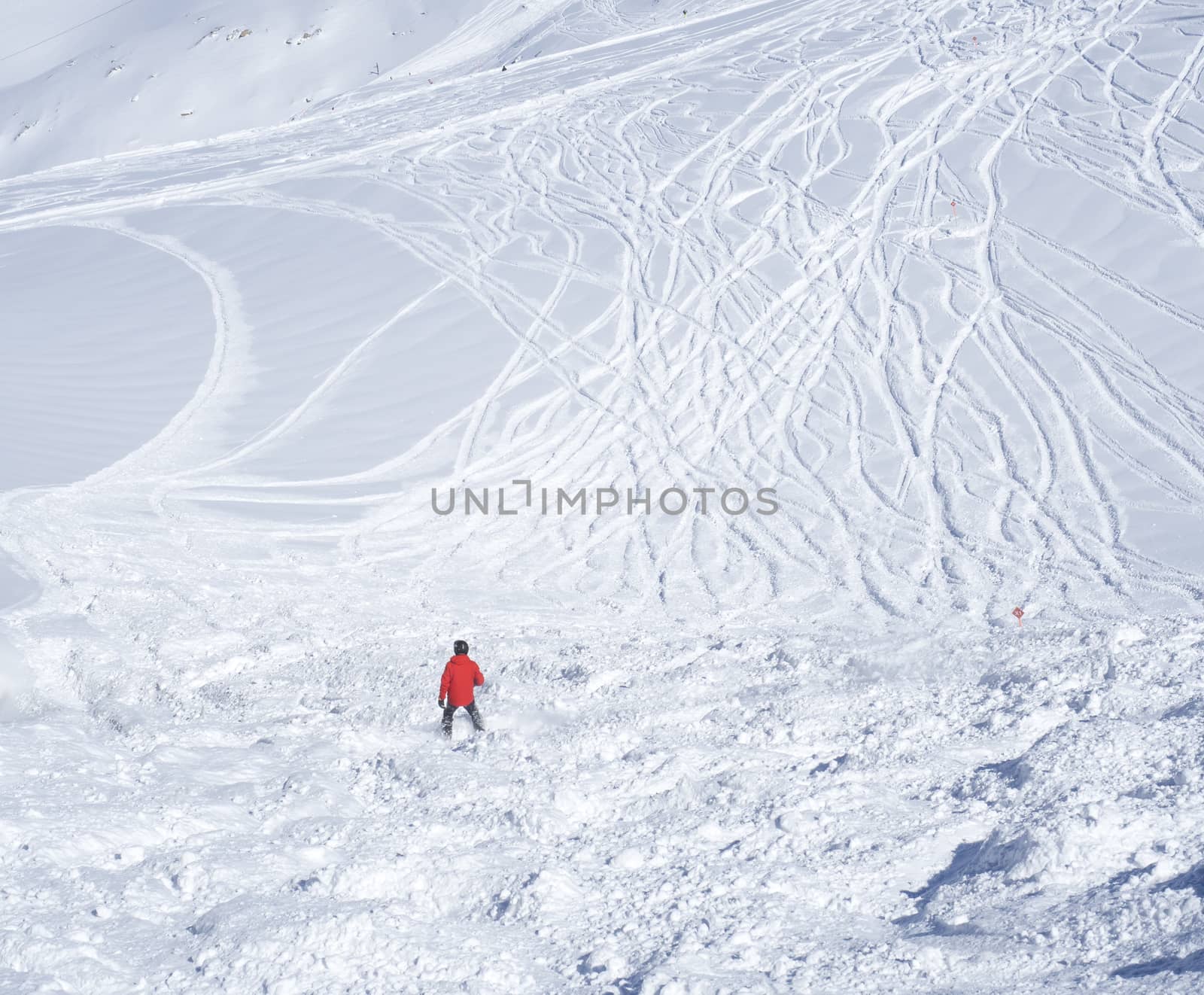 Free ride piste with skier in red clothes skiing downhill on snow covered slopes from the top of Kitzsteinhorn mountain at Kaprun ski resort, National Park Hohe Tauern, Austrian Alps, Europe. Sunny winter day