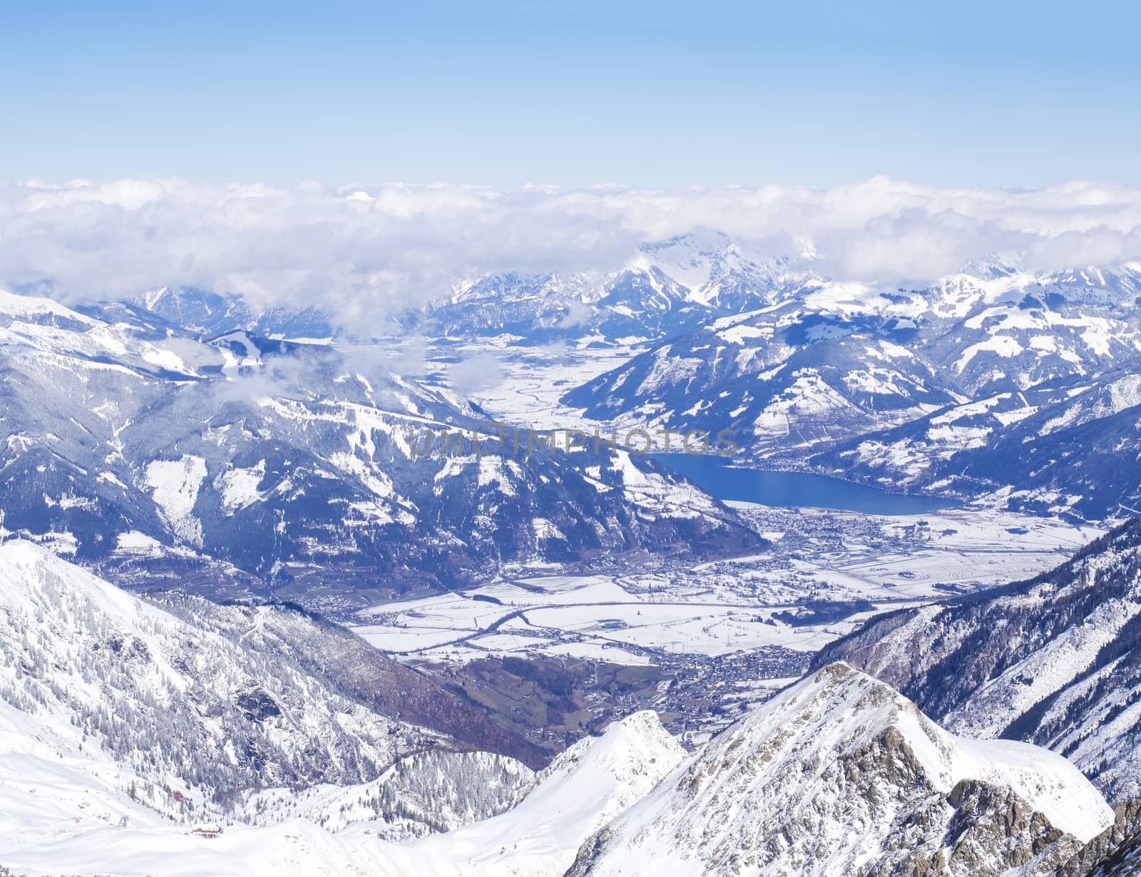 Winter landscape with snow covered slopes and blue sky, with Aerial view of Zell am See lake from the top of Kitzsteinhorn mountain on . Kaprun ski resort, National Park Hohe Tauern, Austrian Alps, Europe