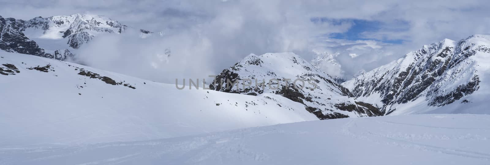 Panoramic view on winter mountain landscape at Stubai Gletscher ski area with snow covered peaks at spring sunny day. Blue sky background. Stubaital, Tyrol, Austrian Alps.