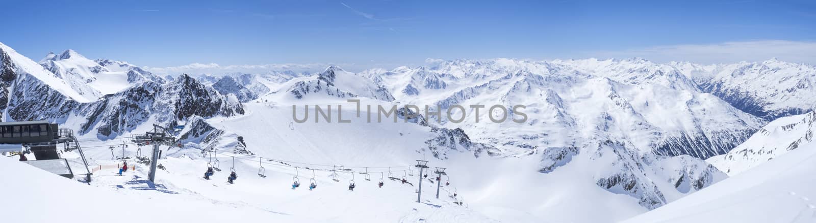Panoramic landscape view from top of Wildspitz on winter landscape with snow covered mountain slopes and pistes and skiers on chair lift at Stubai Gletscher ski resort at spring sunny day. Blue sky background. Stubaital, Tyrol, Austrian Alps by Henkeova