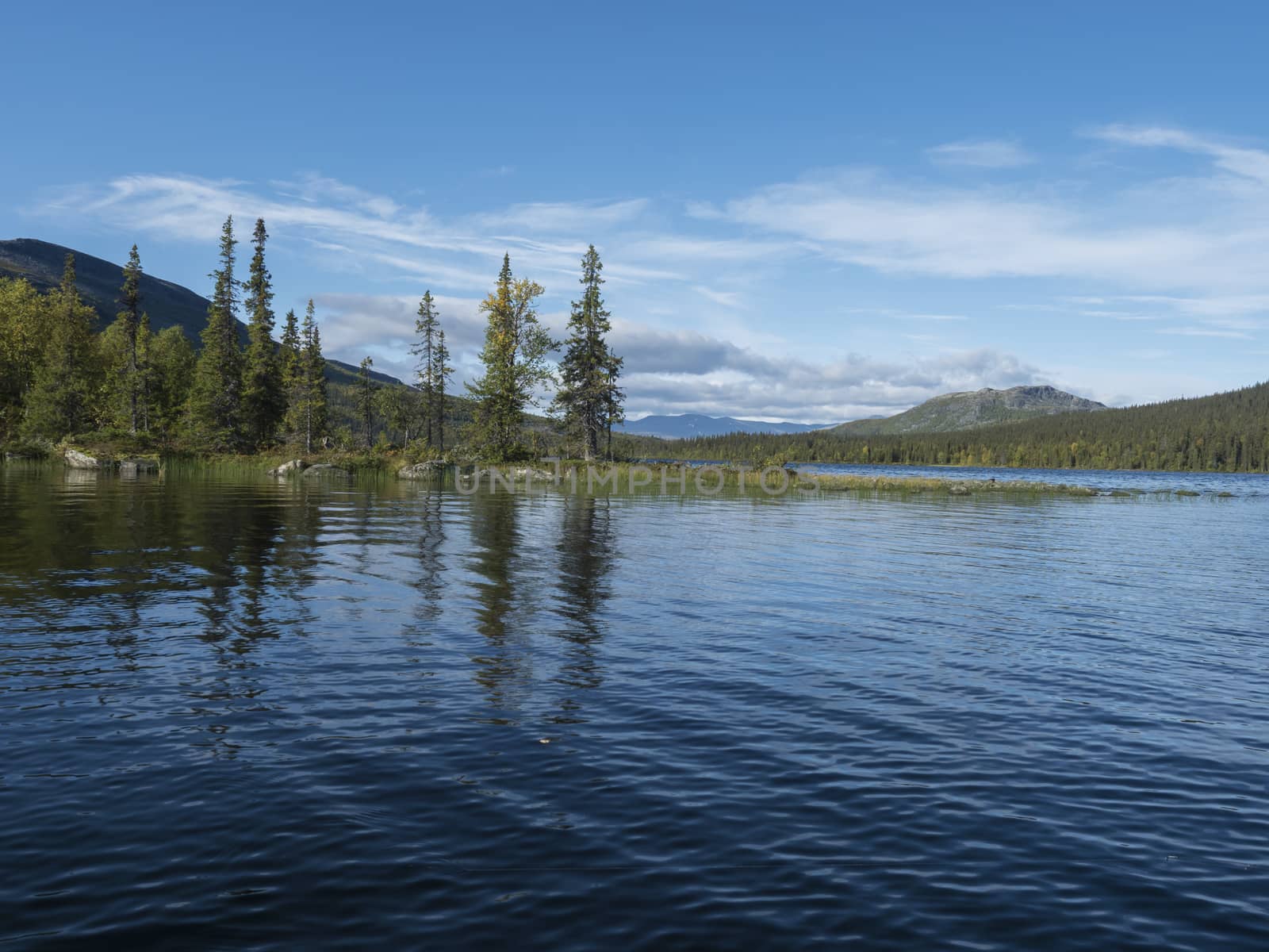 Beautiful morning over lake Sjabatjakjaure in Sweden Lapland nature. Mountains, birch trees, spruce forest, rock boulders and grass. Sky, clouds and clear water. by Henkeova