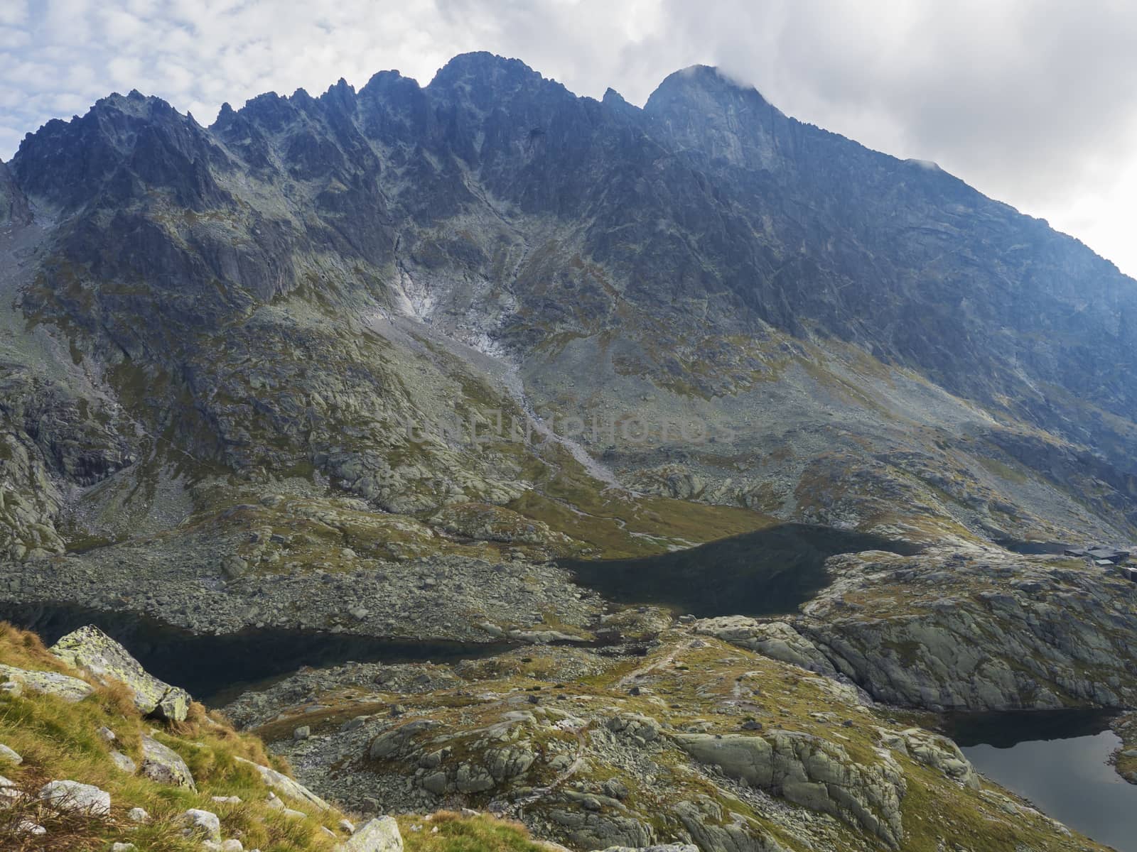 view on three mountain lake Prostredne, Velke and nizne Spisske pleso at the end of the hiking route to the Teryho Chata mountain shelter in the High Tatras in Slovakia, fog nad blue cloudy sky.