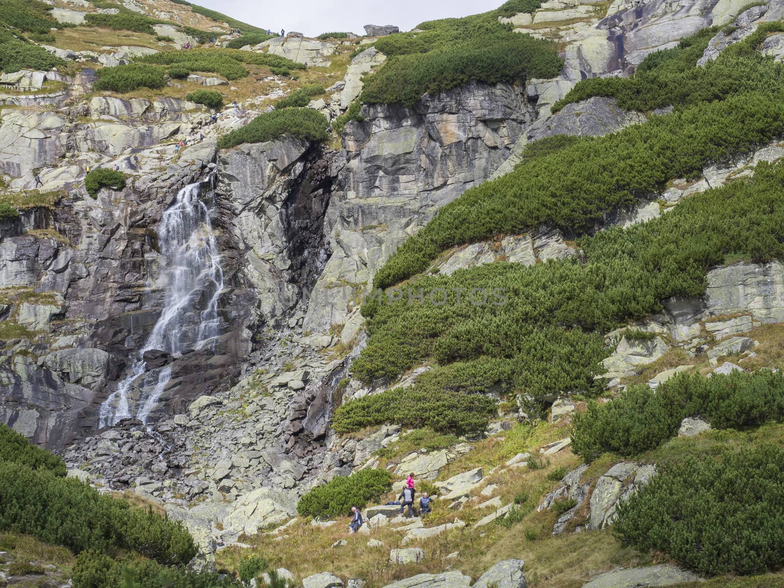 Skok waterfall High Tatras mountain with relaxing tourist people and hikers, summer sunny day, Strbske Pleso, Slovakia.