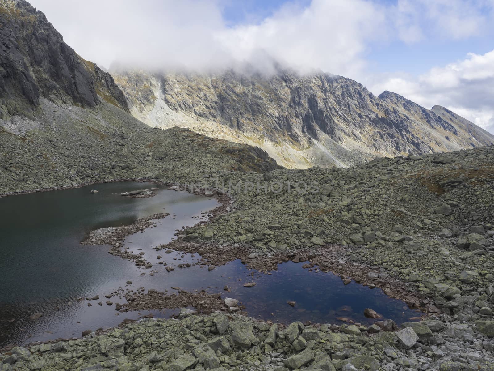 Panorama from Bystra lavka 2300m with the mountain lake Capie and in Mlynicka dolina and peak Strbsky stit 2381m , slovakian high Tatra mountains. fog and dramatic light.