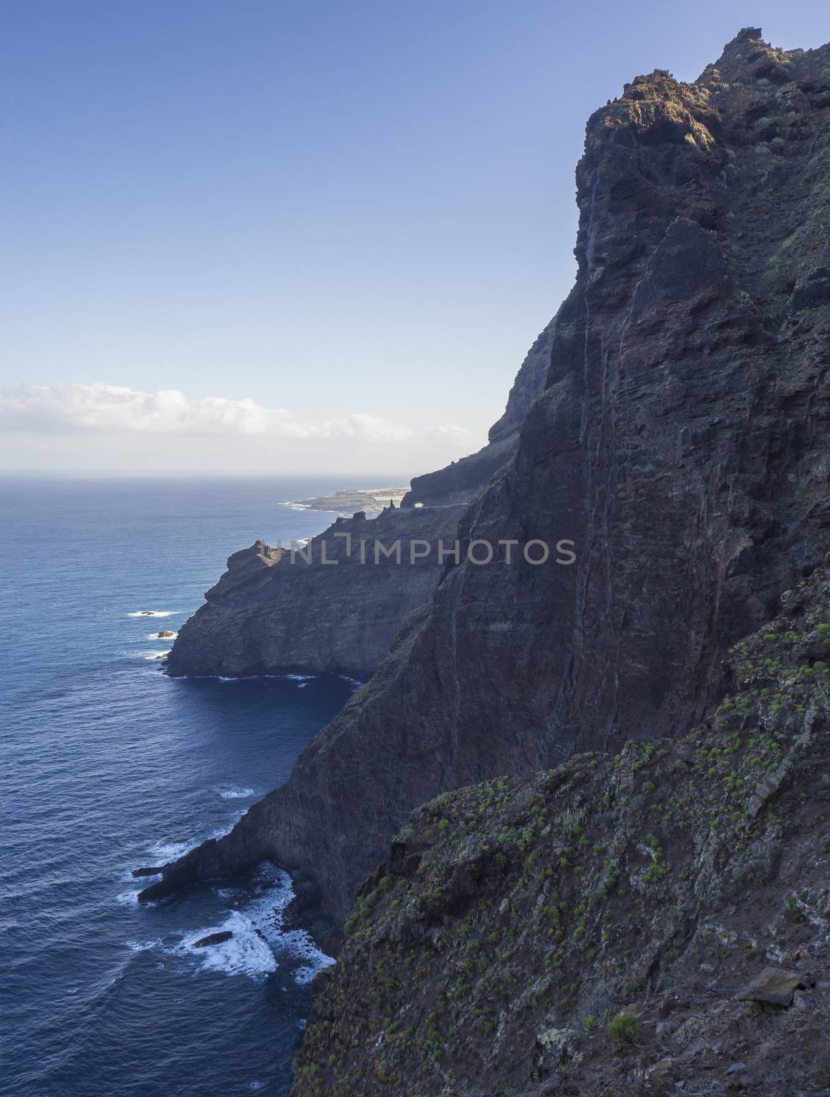 steep high  lava rock cliffs in tenerife blue sea horizon blue sky natural background  by Henkeova
