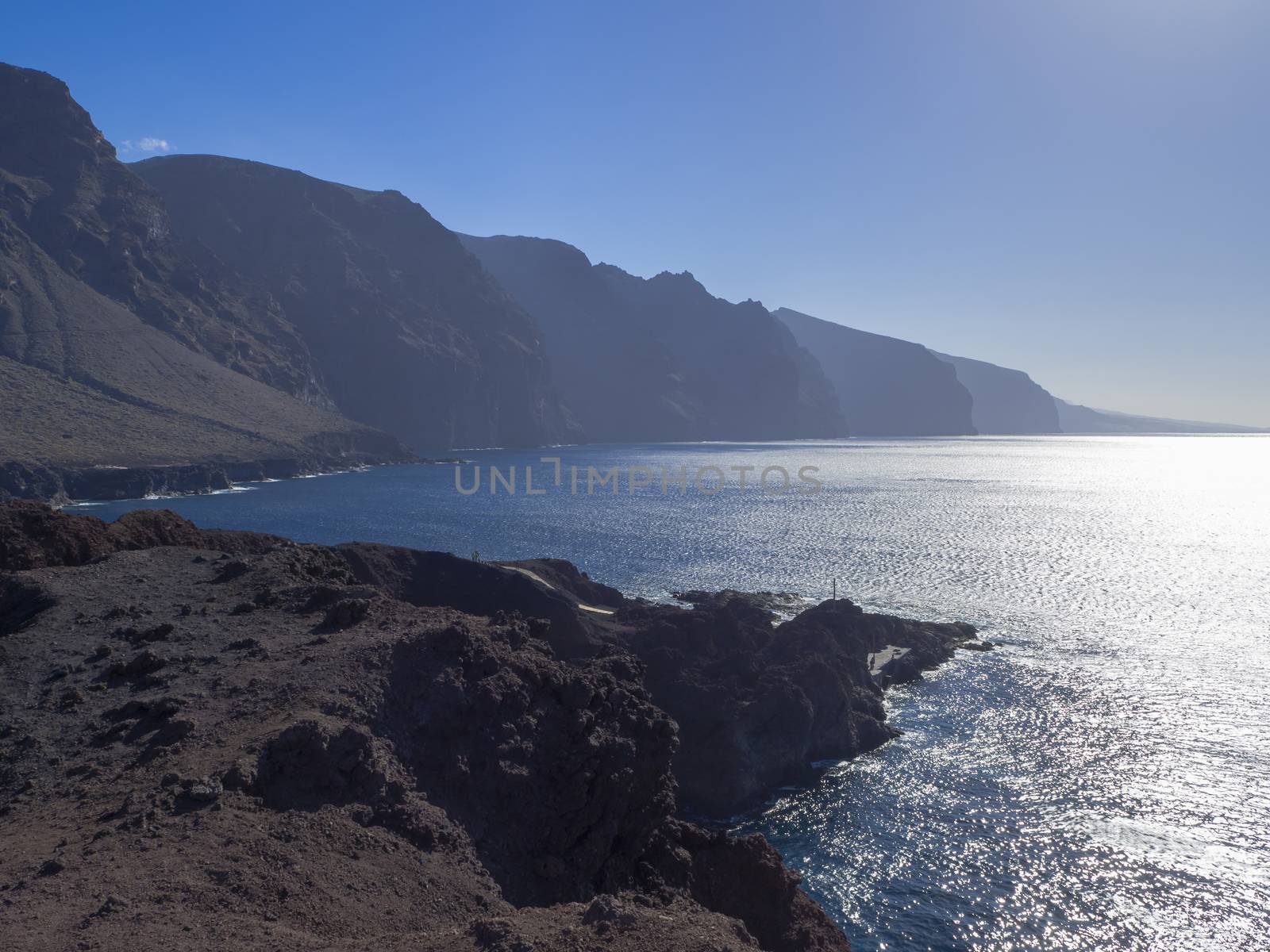 view on hight lava cliffs los gigantes on Punta de Teno cape on west Tenerife canary island with lava rock blue sea and clear summer sky Contre-jour against daylight