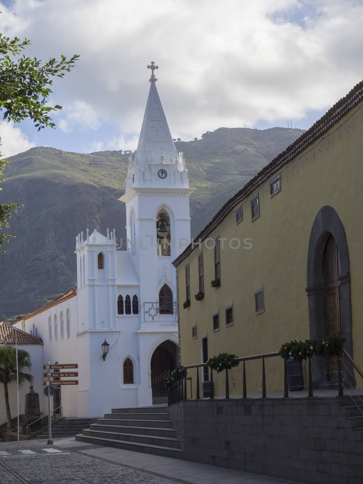 white church and historic buildings in old village Los Silos in tenerife Canary Islands with green hills in background