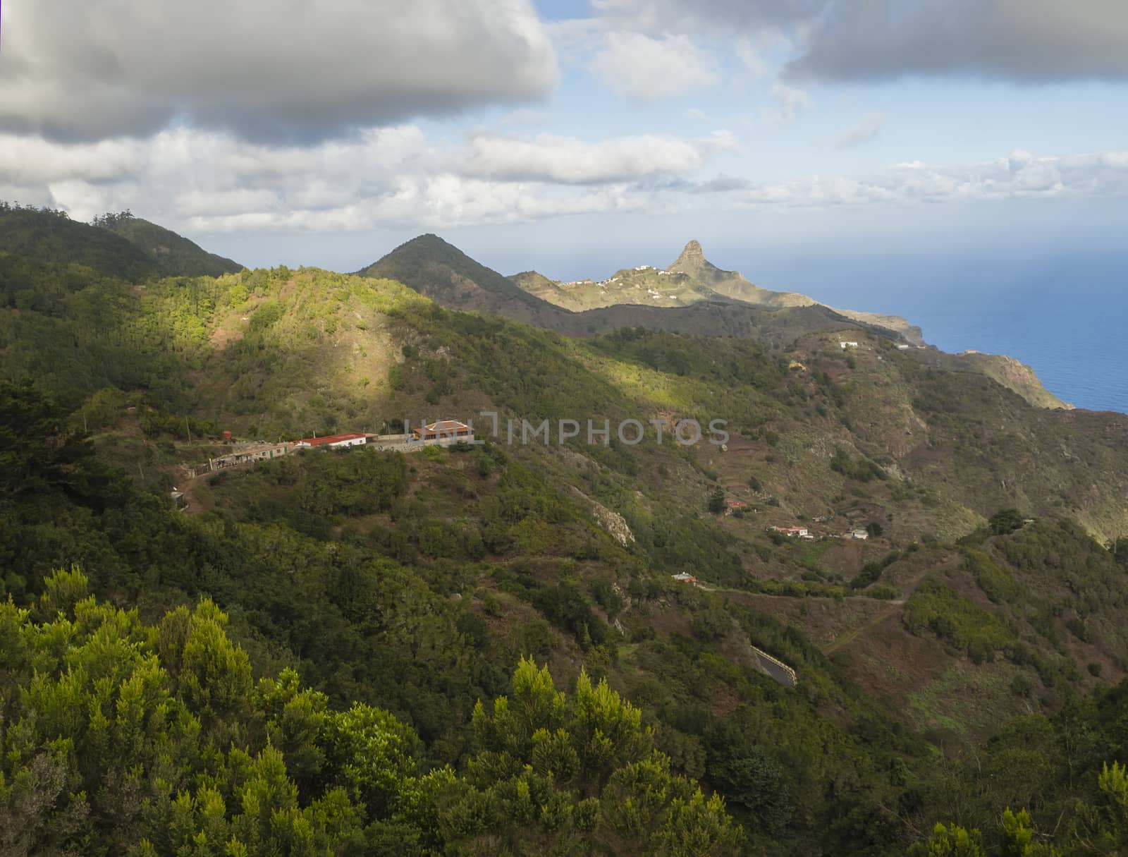 view on Monte Taborno with green hills, houses and blue sky white clouds in anaga mountain, tenerife canary island spain