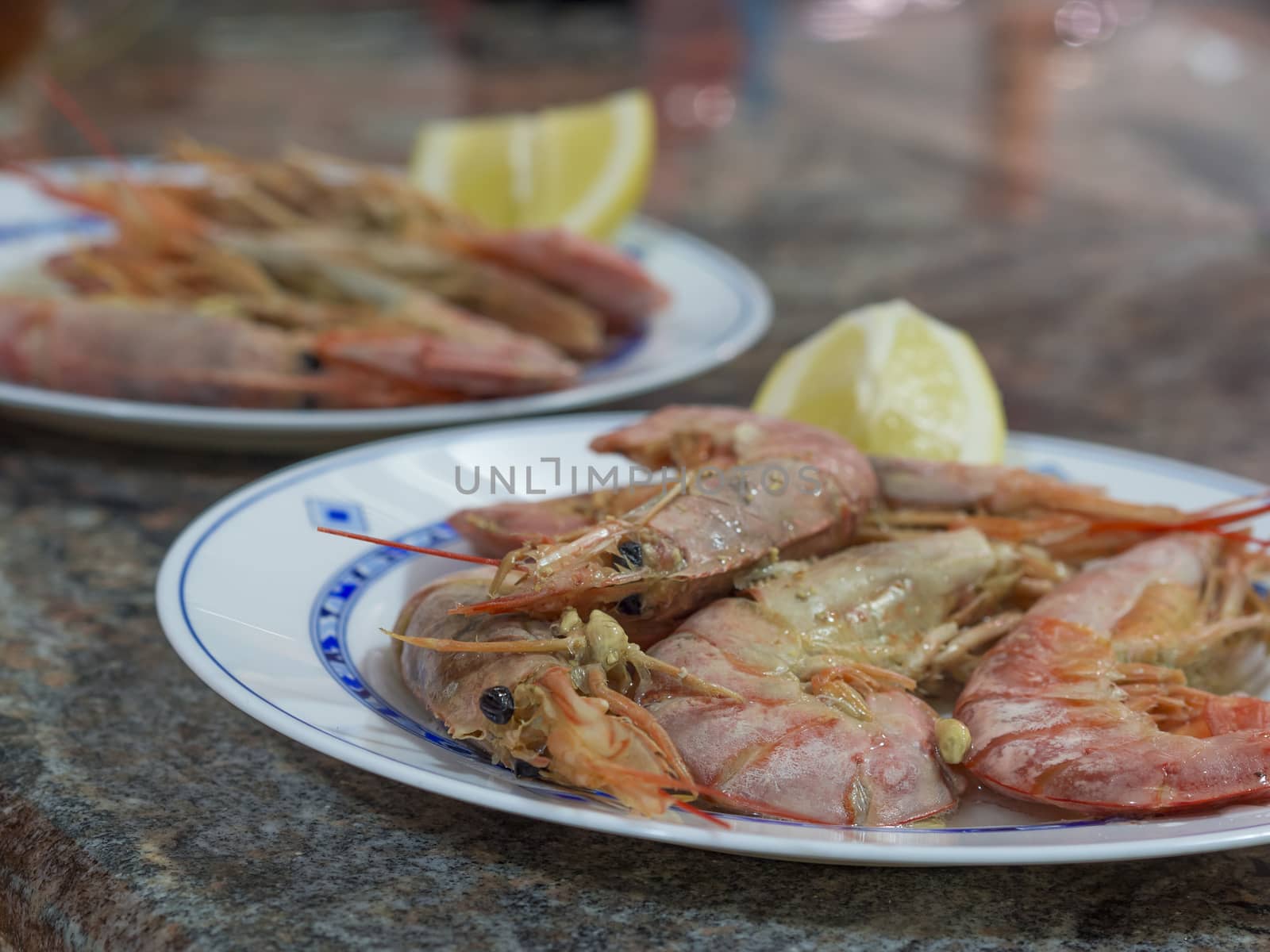 close up boiled giant red prawns with lemon and garlic on plate on marblel desk