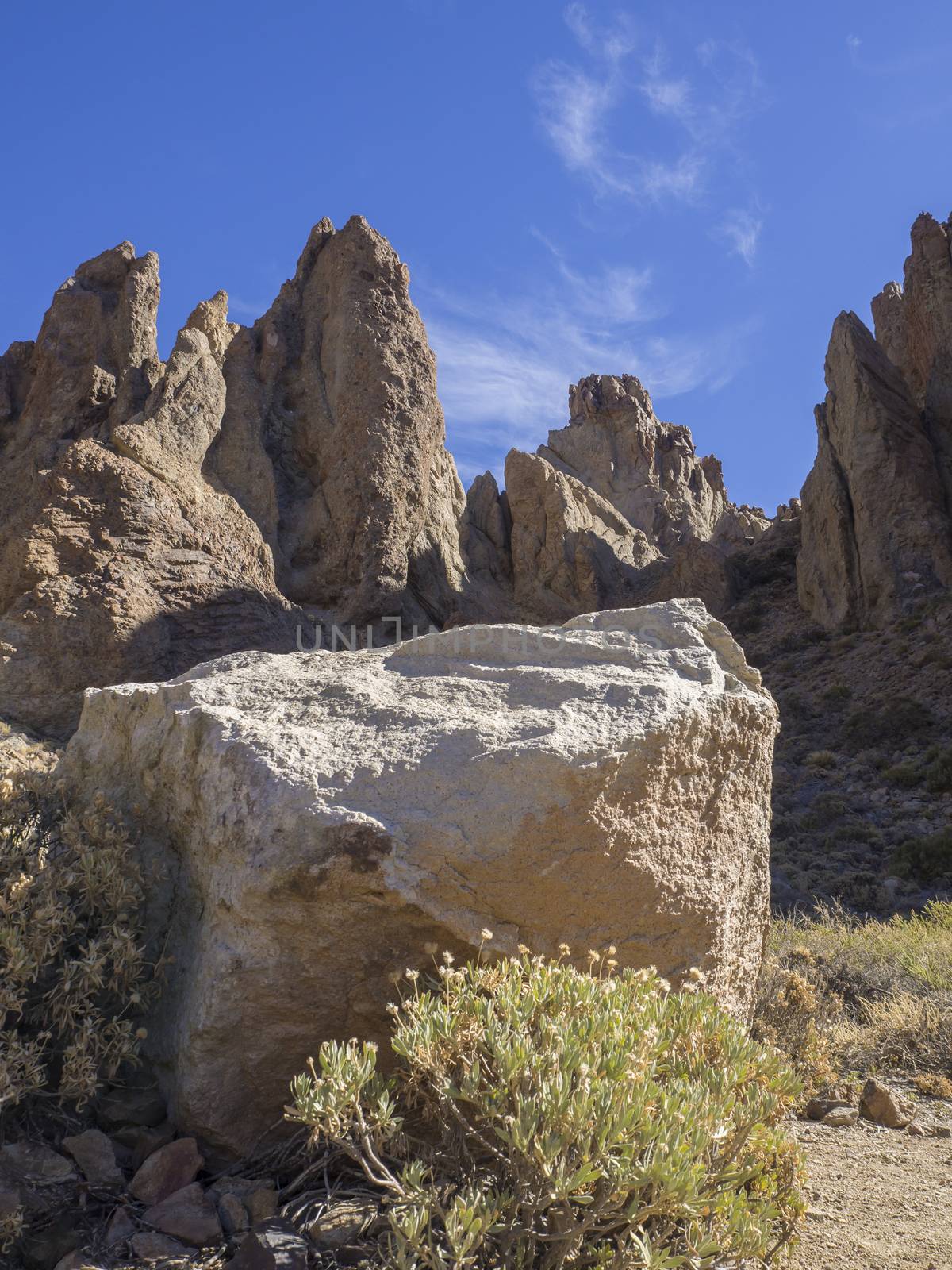 big white square stone with view on famous rock formation Roques de Garcia on tenerife canary island unesco protected landscape, blue sky background by Henkeova