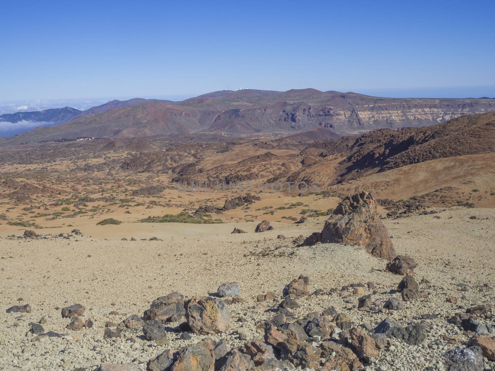 desert volcanic landscape on Tenerife with purple mountains in el teide national nature park with Huevos del Teide (Eggs of Teide) lava balls rocks, clear blue sky background