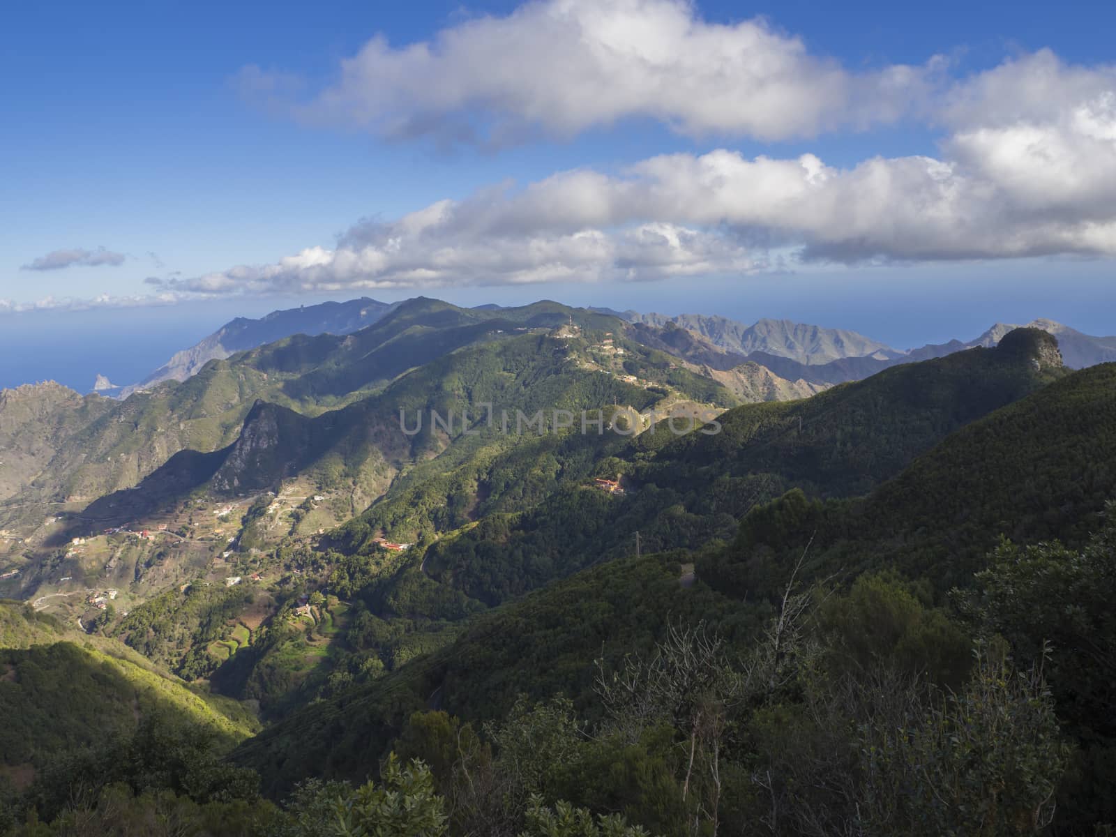 view point Amogoje, green hills with rock in the sea El Draguillo in anaga mountain, tenerife  canary island spain with dramatic blue sky white clouds background