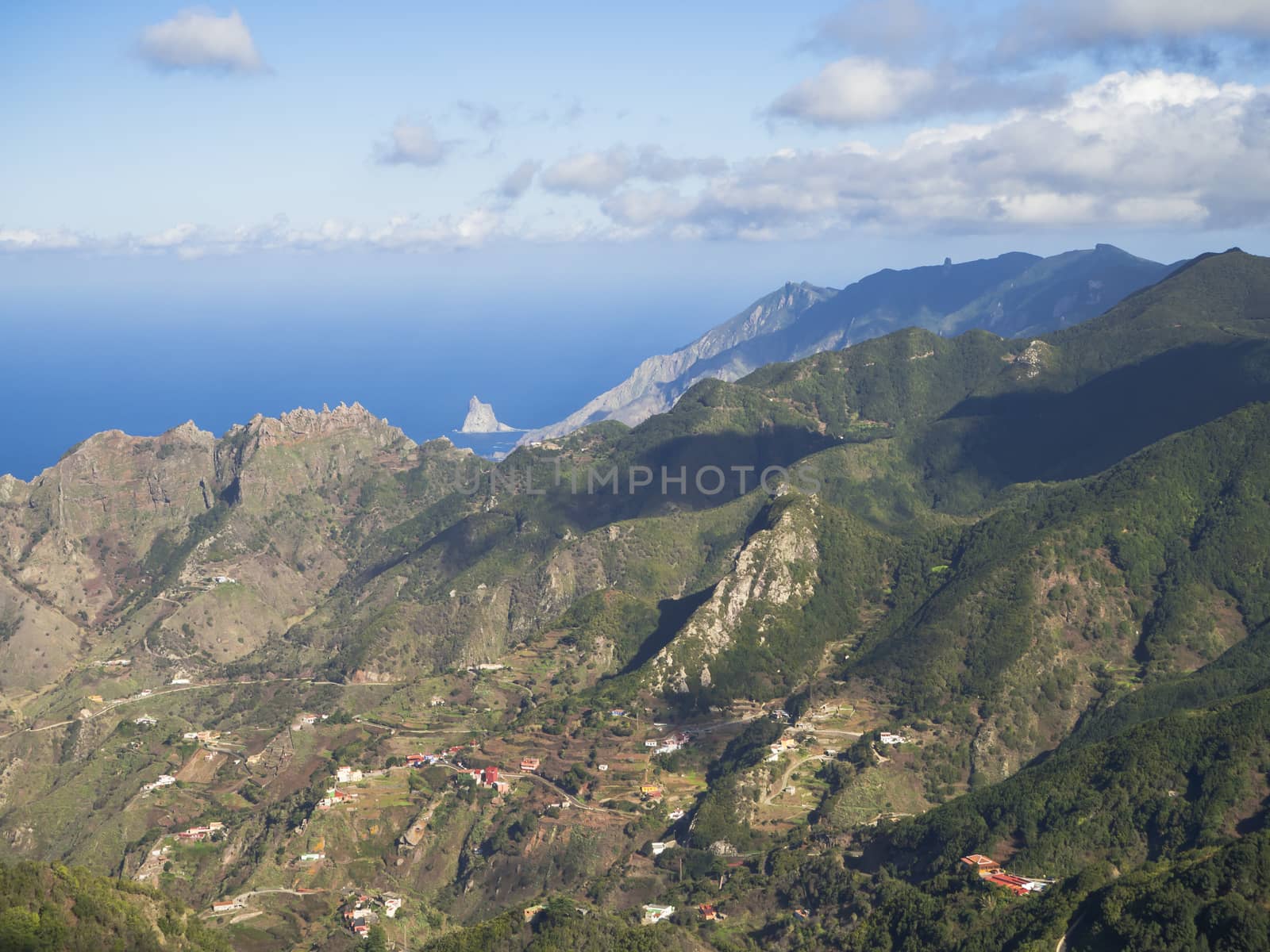 view point Amogoje, green hills with rock in the sea El Draguillo in anaga mountain, tenerife  canary island spain with dramatic blue sky white clouds background