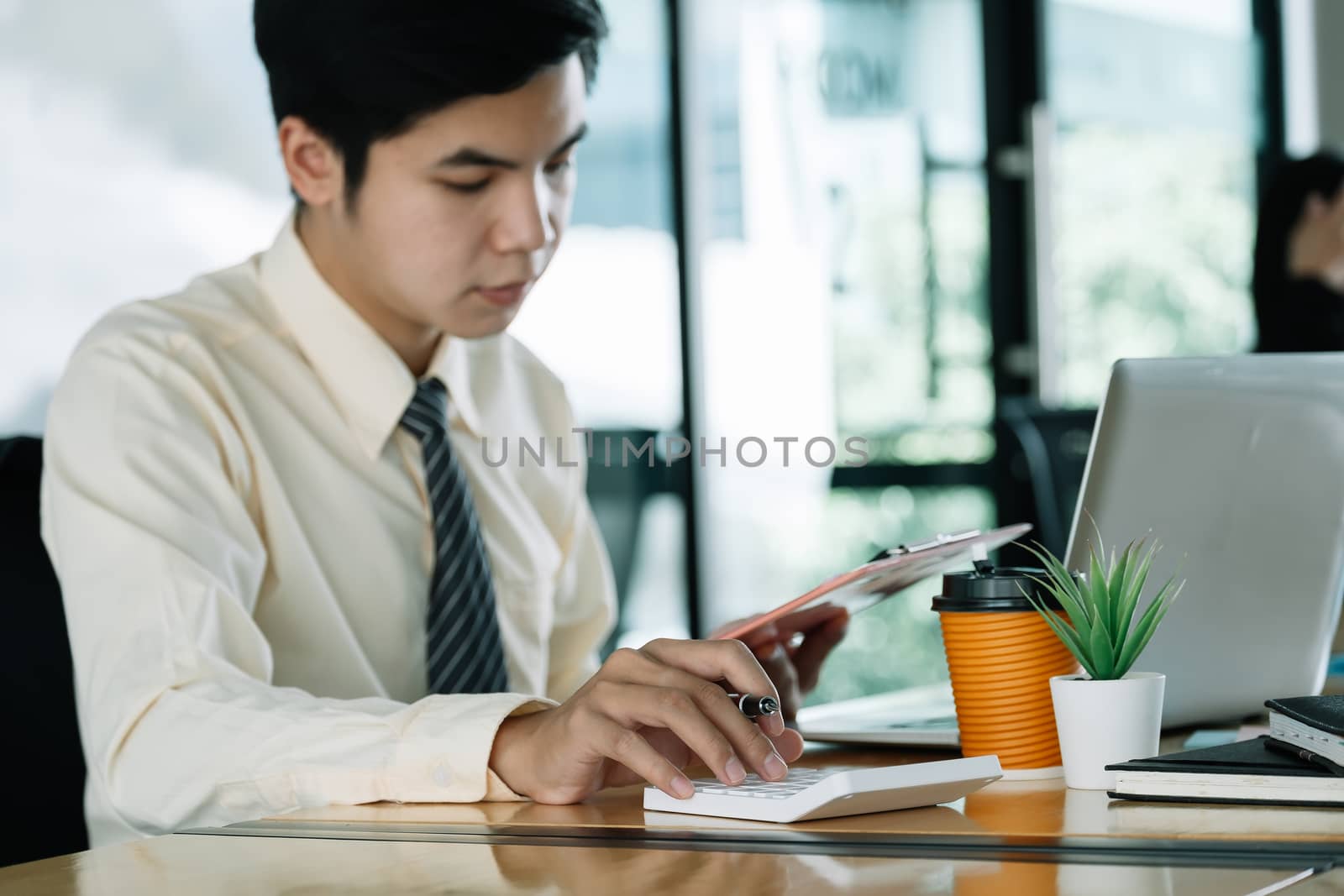 businessman or accountant hand holding pencil working on calculator to calculate financial data report, accountancy document and laptop computer at office, business concept.