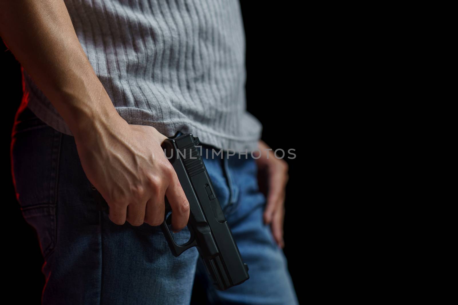 Man holding a gun side him on black background.