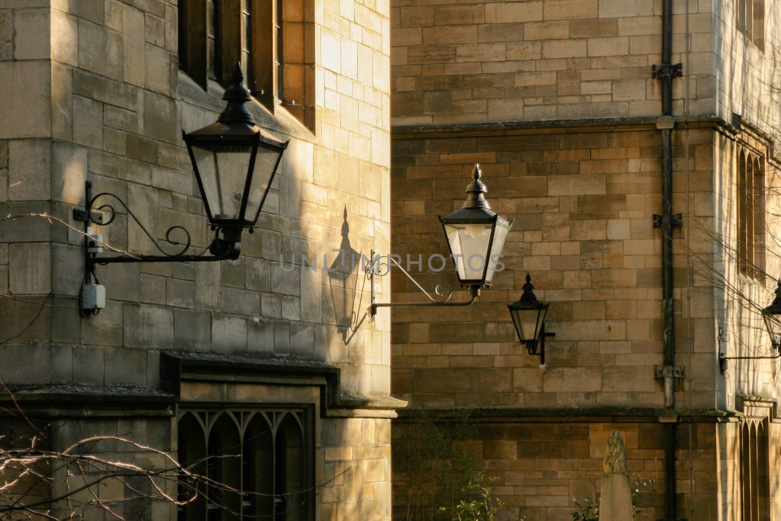 Victorian style street lighting lanterns against Oxford College in afternoon sun by kgboxford