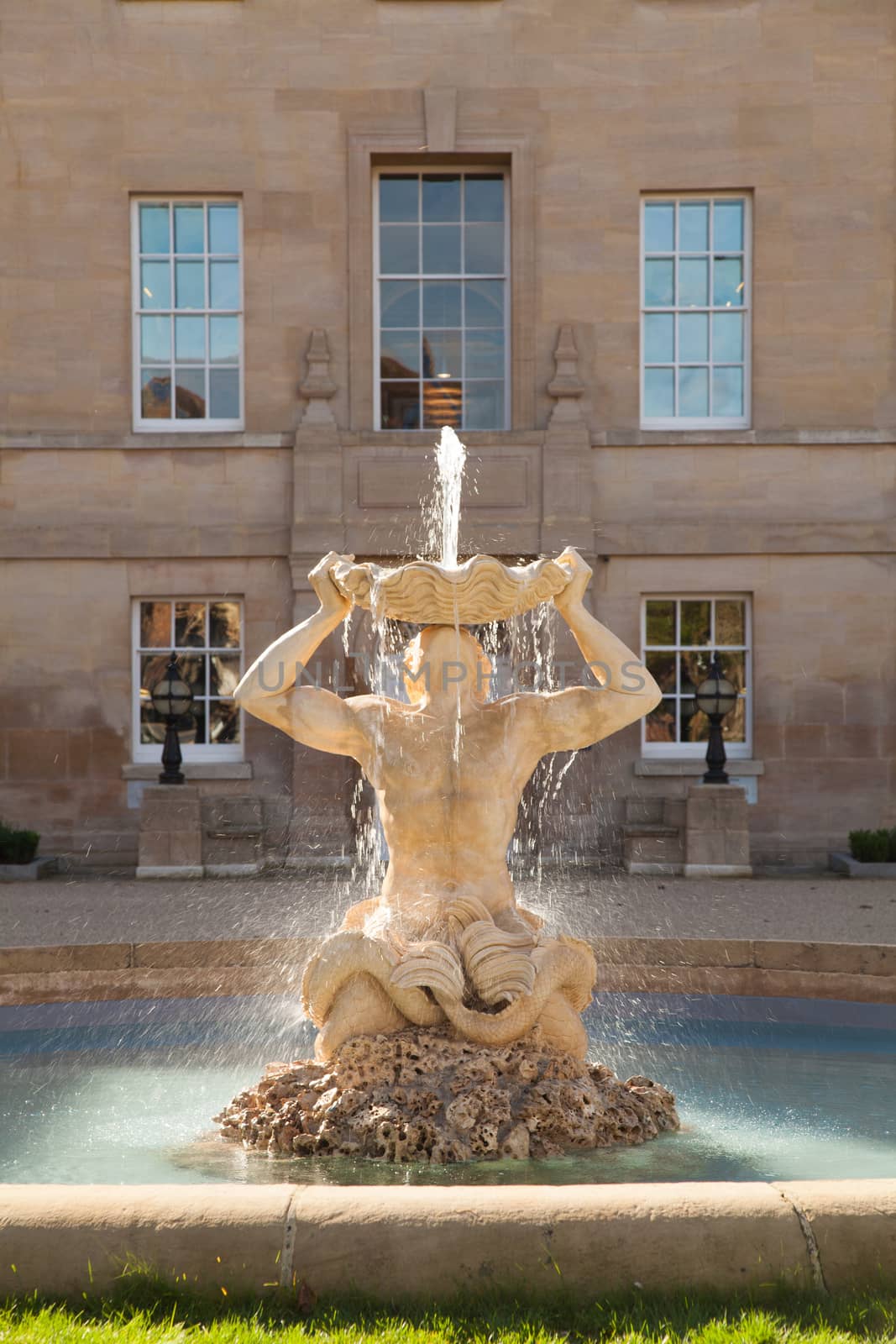 Oxford, UK 6th October 2013 Landscape view of fountain backlit with low sun and lens flare showing beautiful water flow. Copy of Bernini's Triton fountain from the Piazza Barberini. 