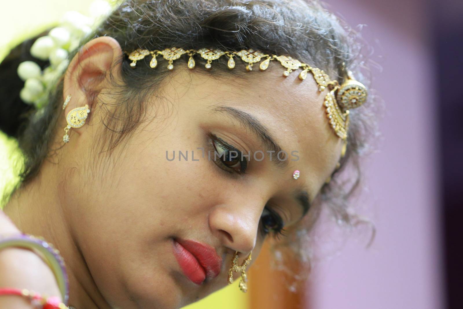 The face of a beautiful north india girl with traditional Rajasthani head gold jewellery (Maang tikka). by 9500102400