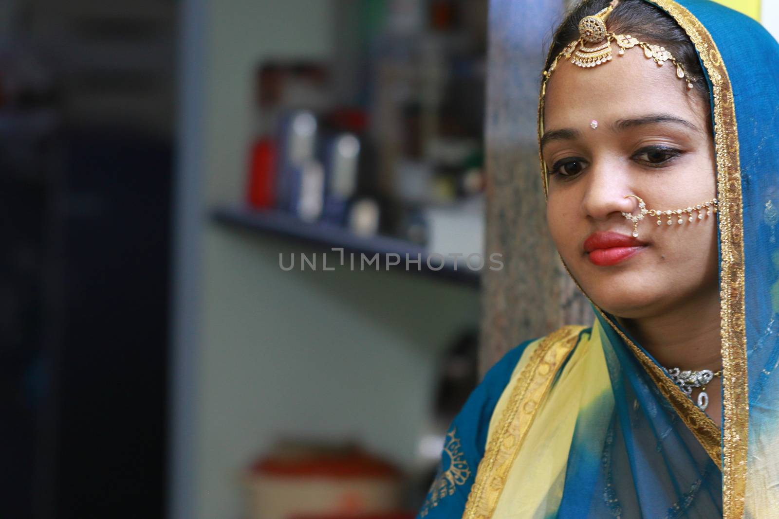 Indoors portrait of woman with traditional Rajasthani head gold jewellery (Maang tikka).