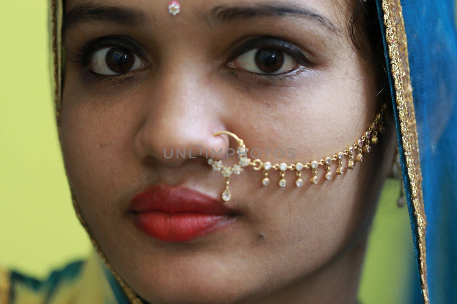 Closeup of a beautiful north india girl with traditional Rajasthani styles Nath gold jewellery by 9500102400