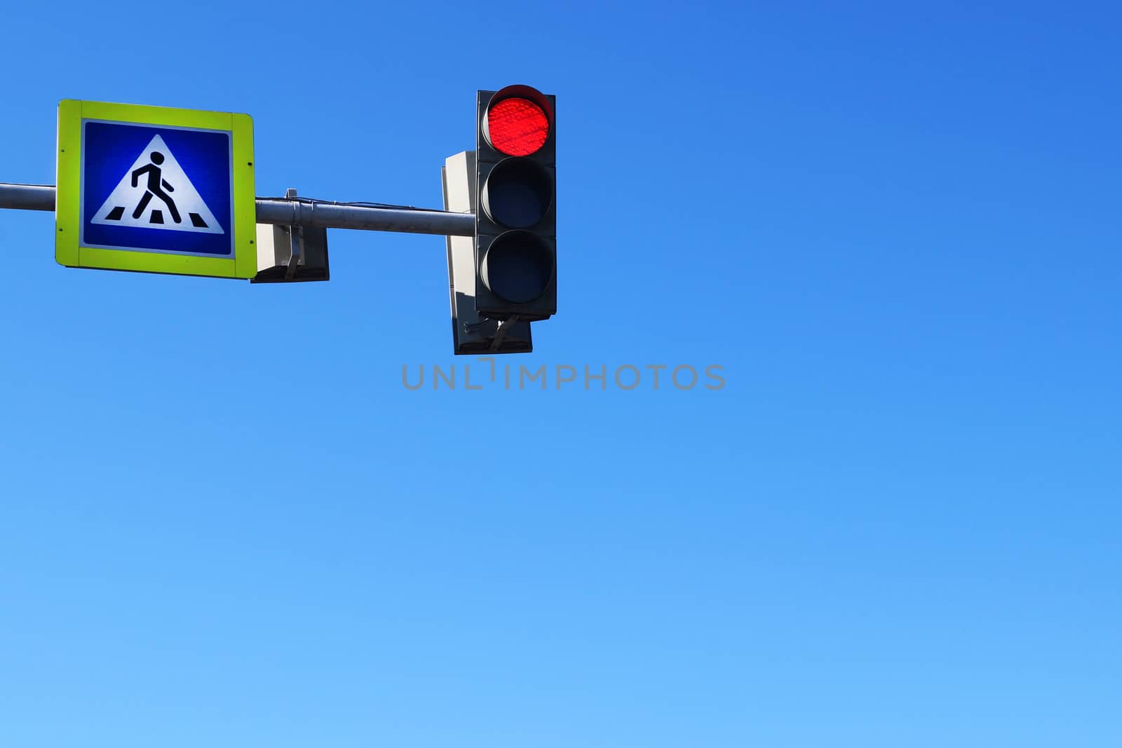 crosswalk sign and red traffic light on blue sky background, copy space.