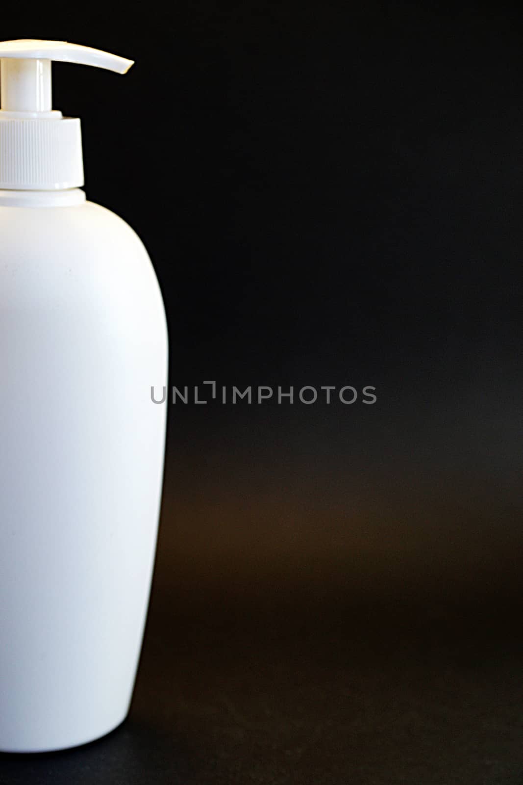 white cosmetic bottle with spray on black background close-up by Annado