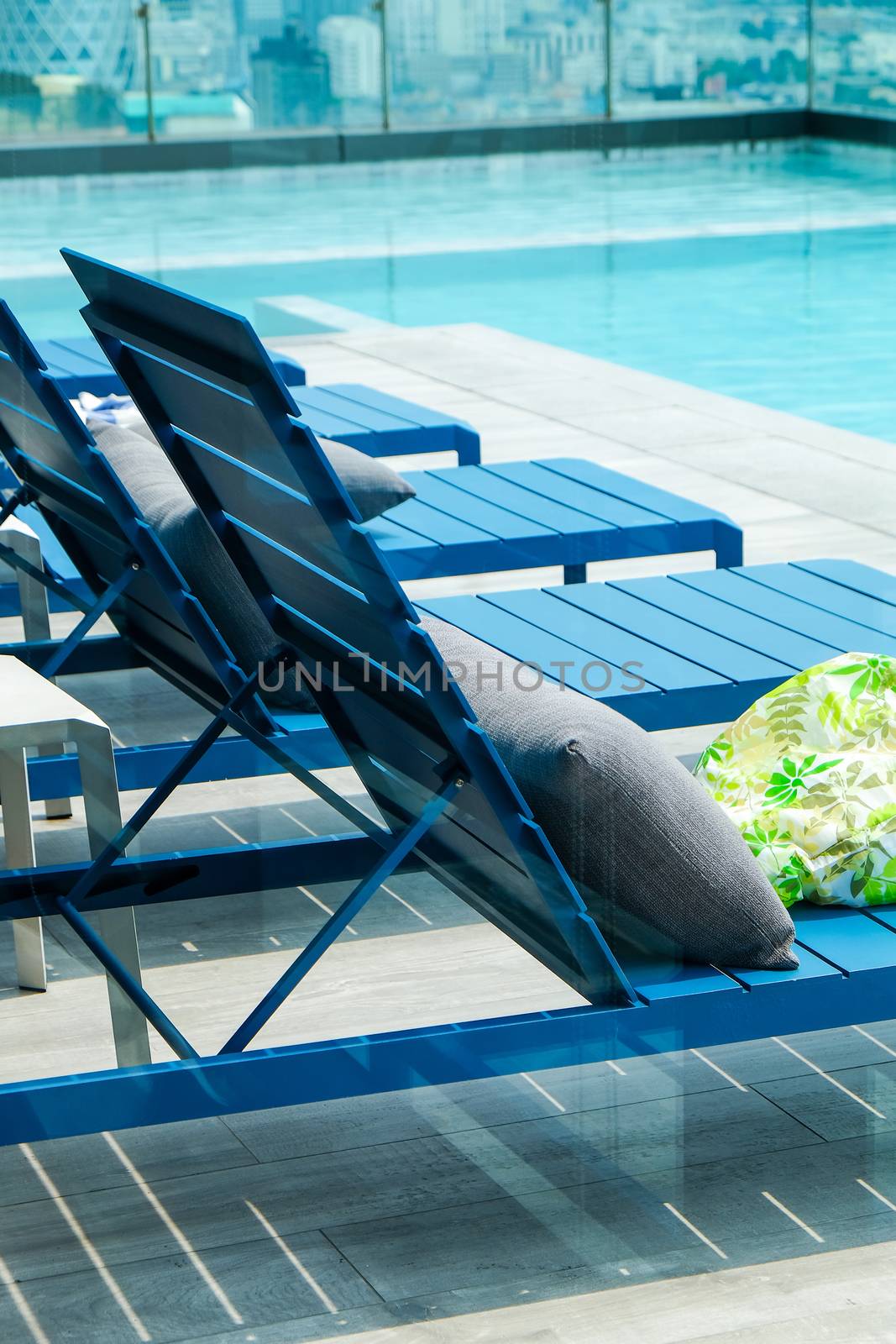 Swimming pool with chaise loungers background by ponsulak
