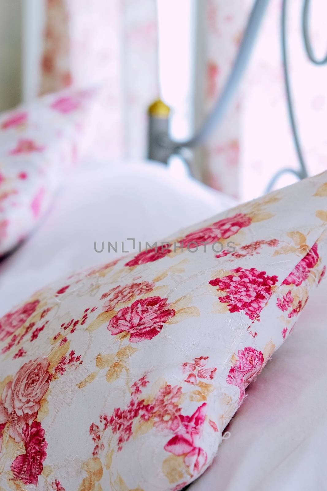 Bright bedroom interior with flower pattern pillows on bed by ponsulak