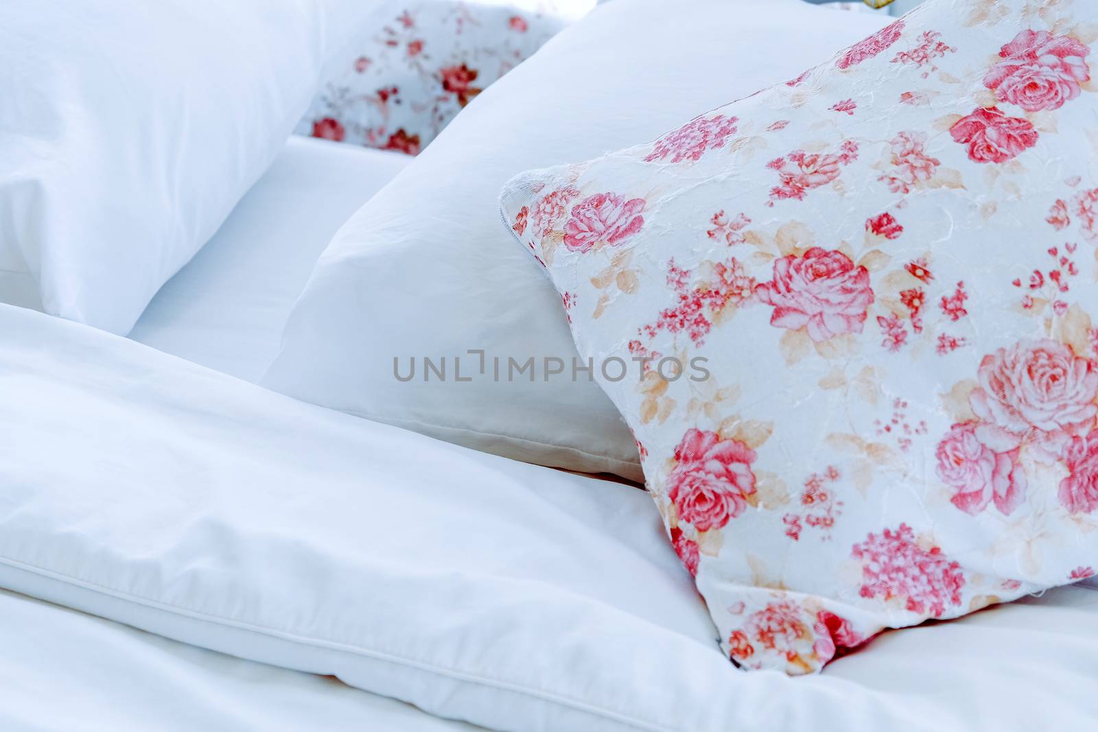Bright bedroom interior with flower pattern pillows on bed
