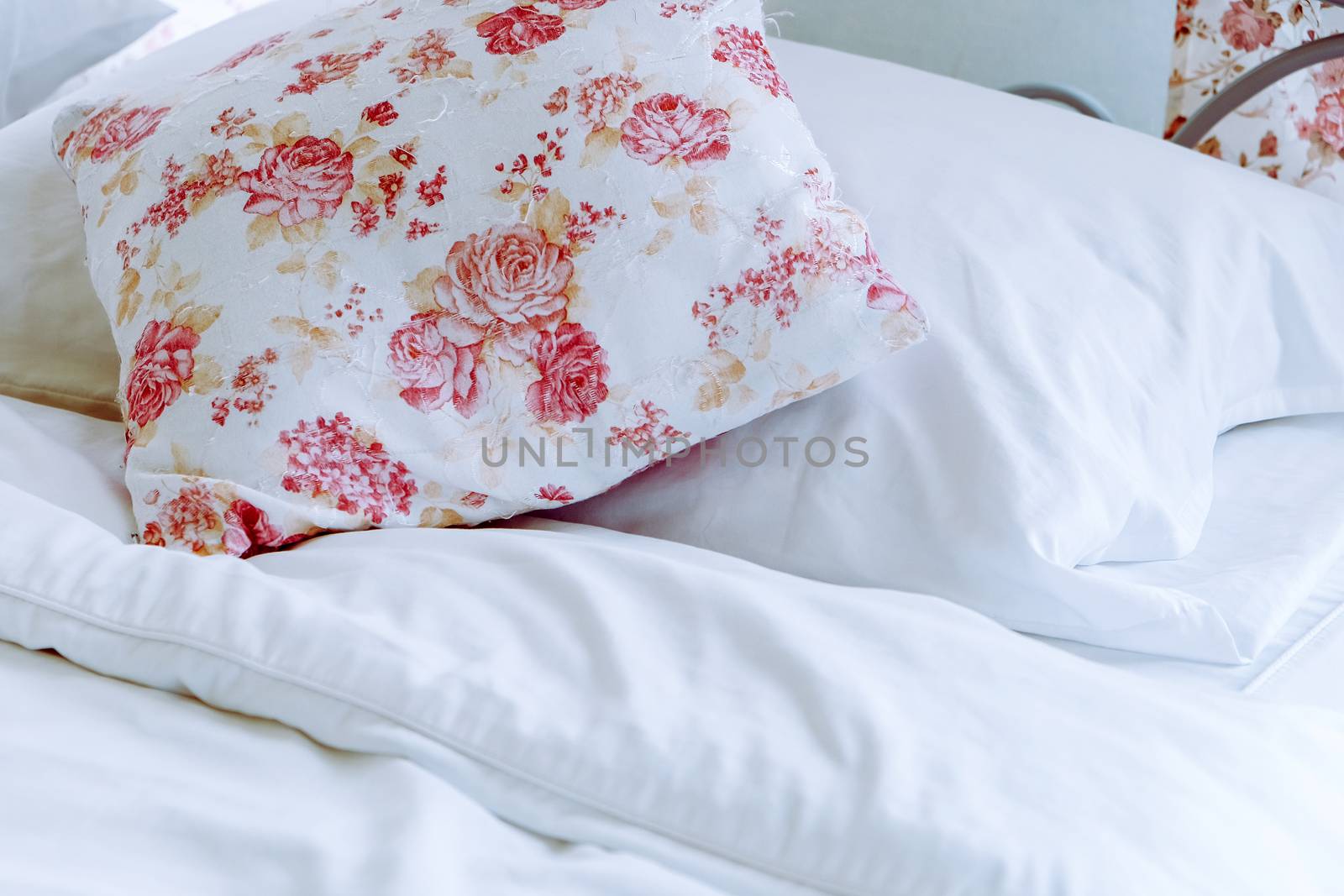 Bright bedroom interior with flower pattern pillows on bed