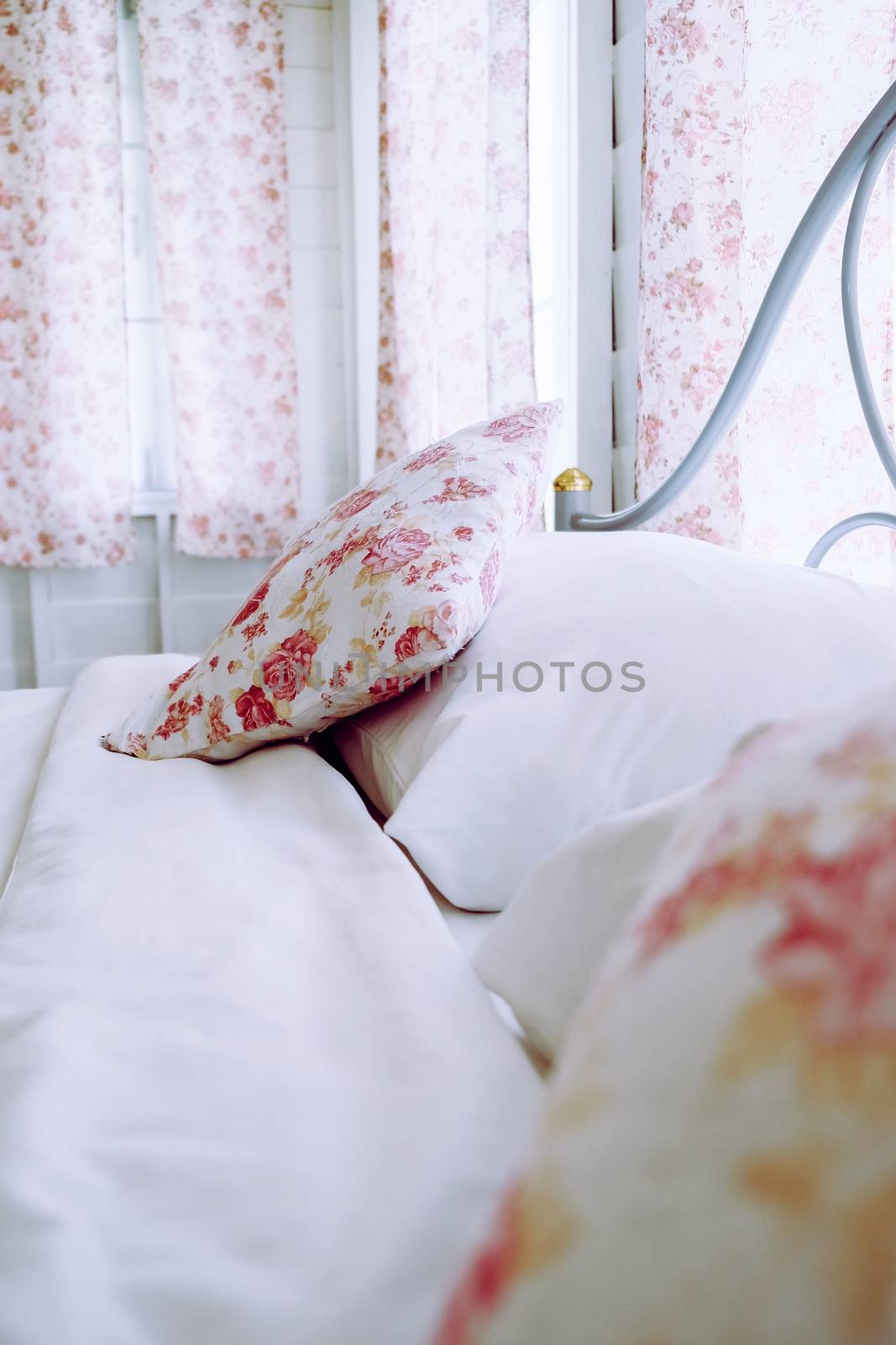 Bright bedroom interior with flower pattern pillows on bed by ponsulak