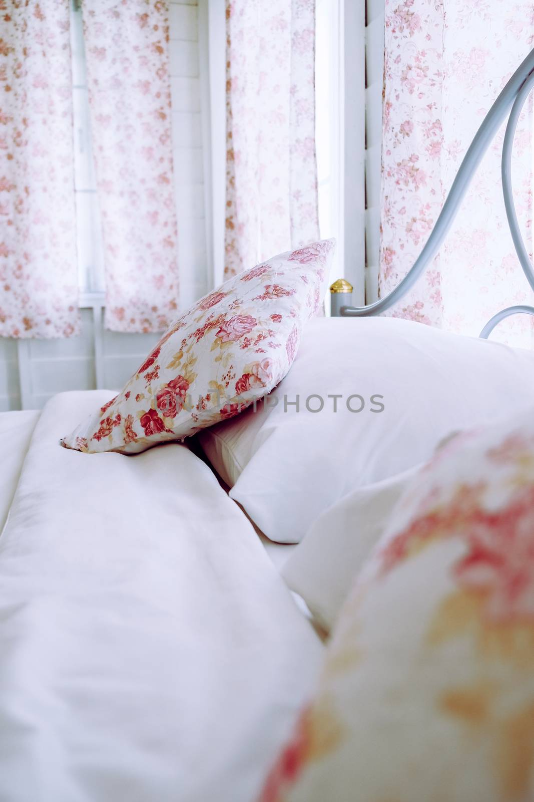 Bright bedroom interior with flower pattern pillows on bed