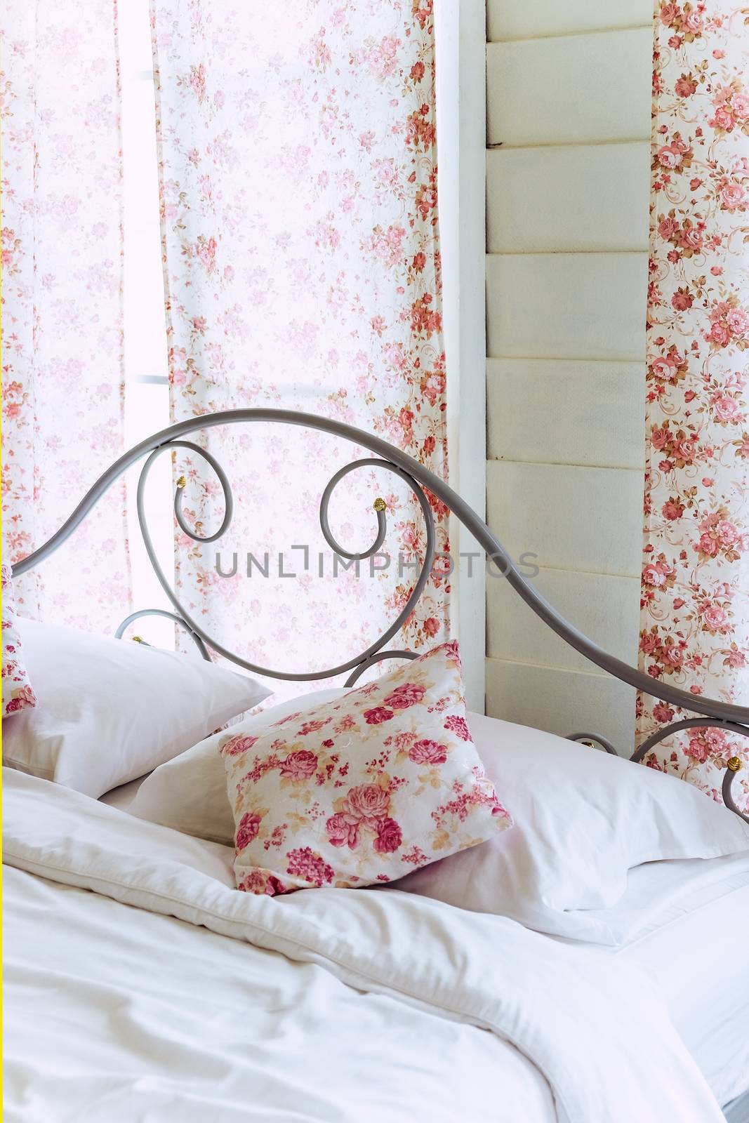 Bright bedroom interior with flower pattern pillows on bed by ponsulak