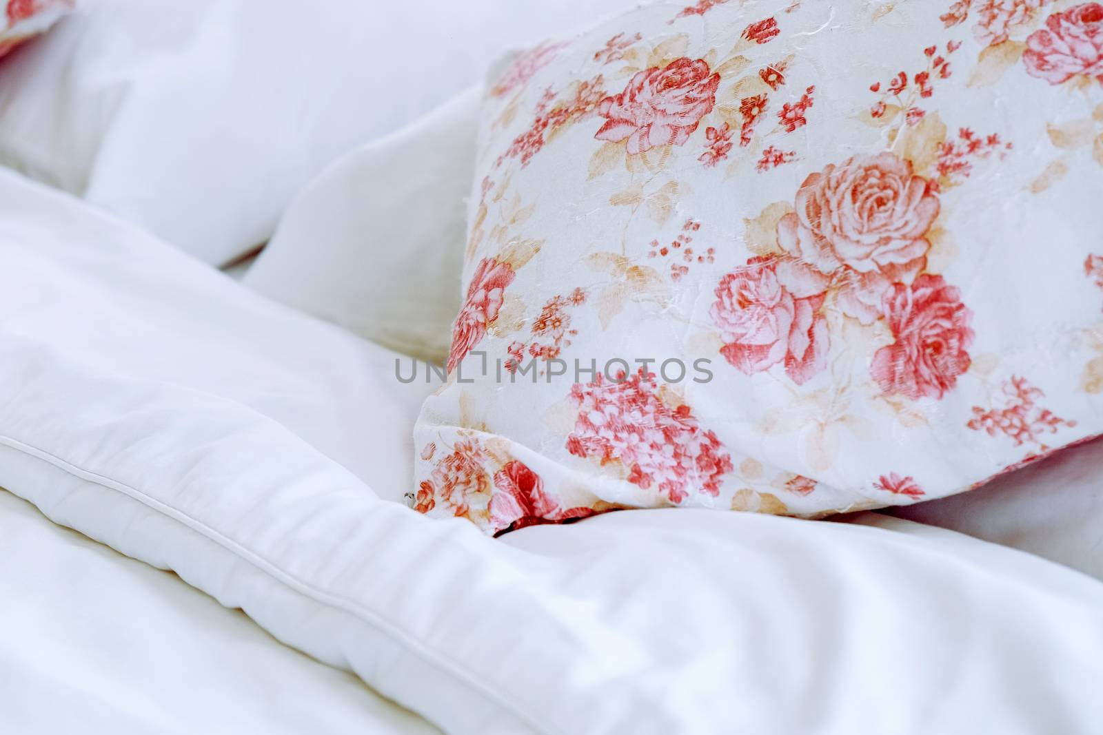Bright bedroom interior with flower pattern pillows on bed