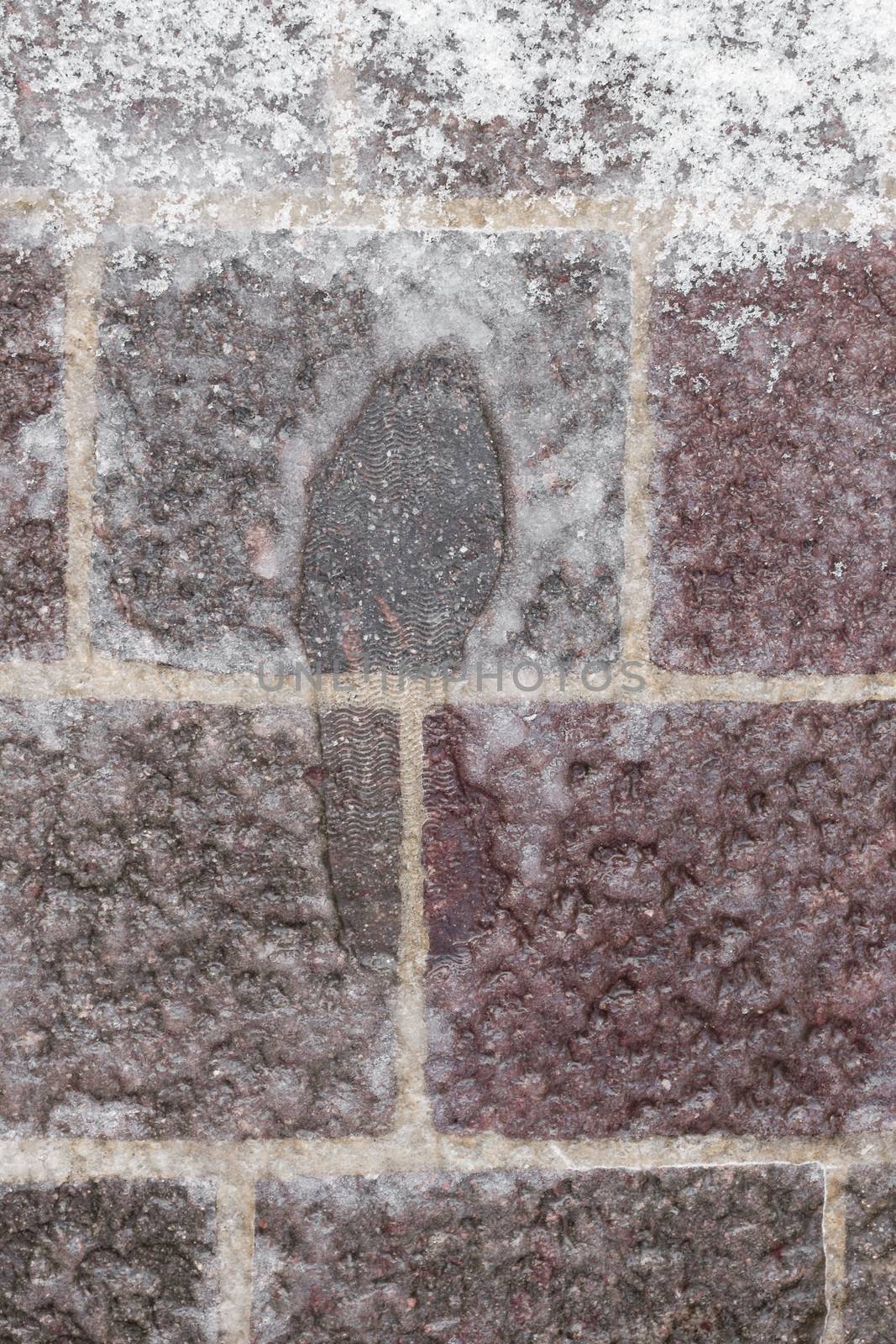An imprint of the shoe in the icy snow.
