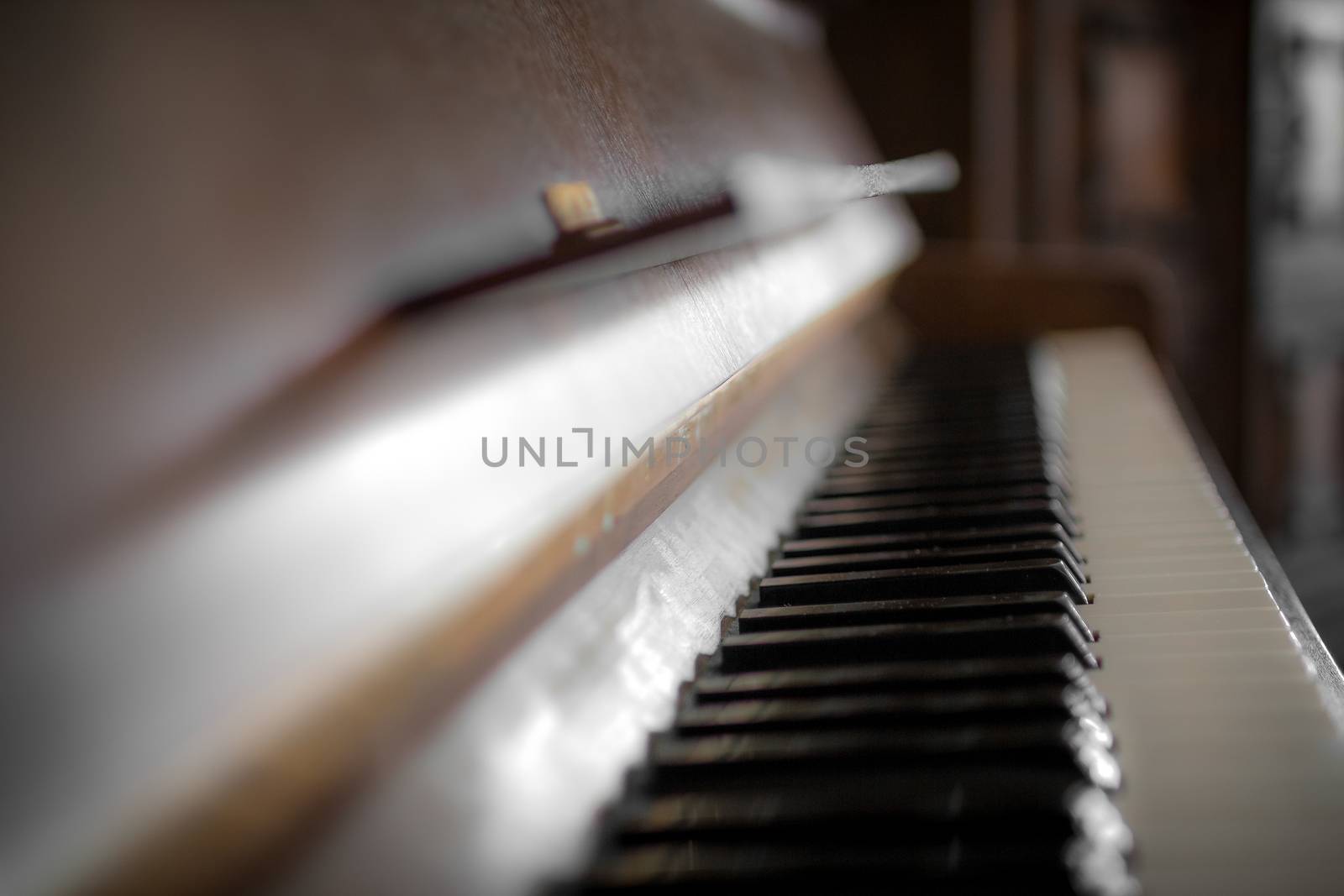 Closeup of a piano keyboard in brown wood.
