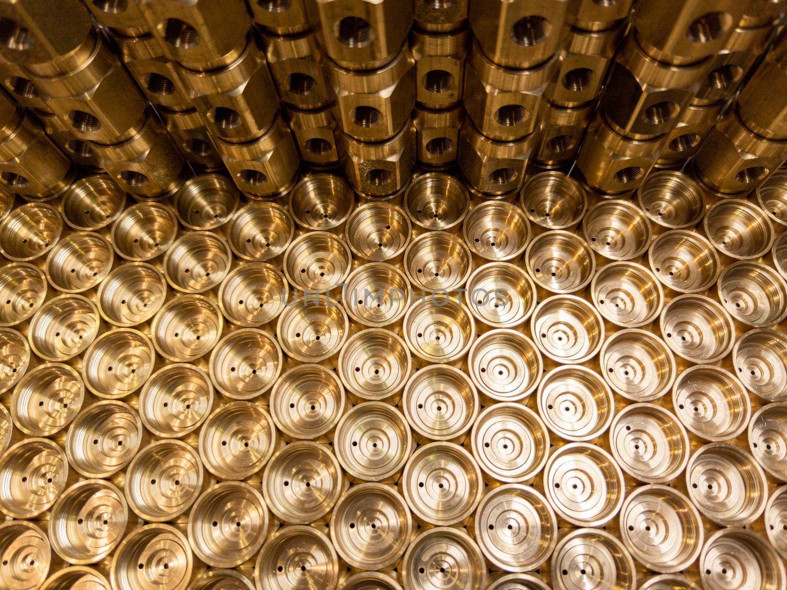 an abstract industrial close-up background of shiny brass metal threaded hexagonal fitting parts.