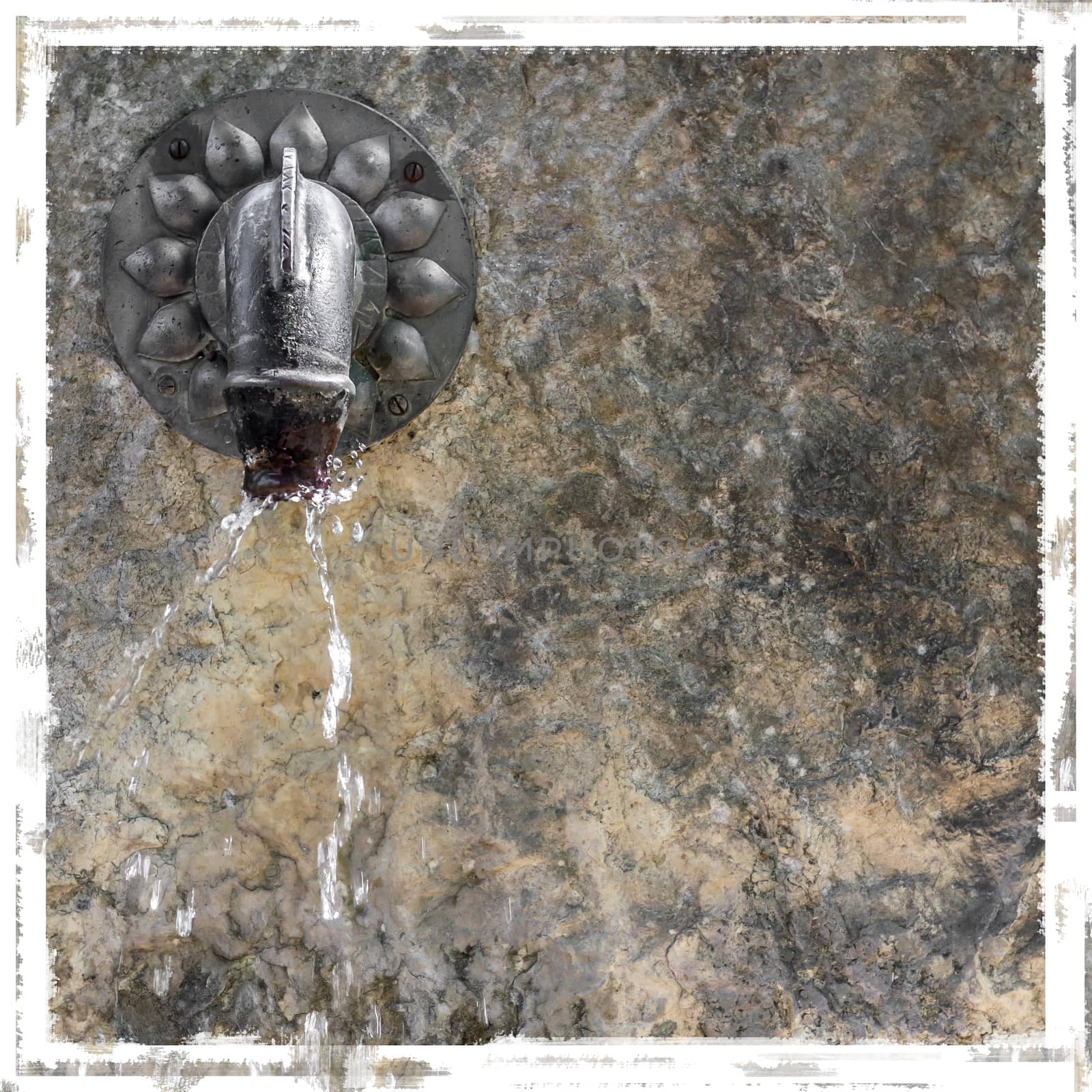 Close-up view of old water fountain with stone wall. Vintage style frame.