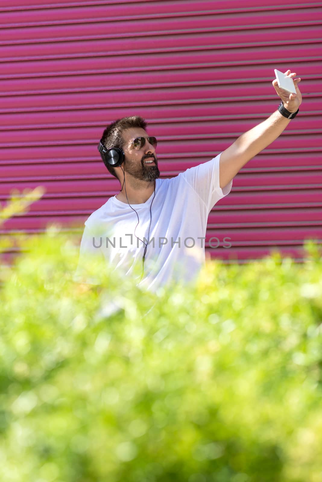 Bearded man with sunglasses taking a selfie against pink wall by raferto1973