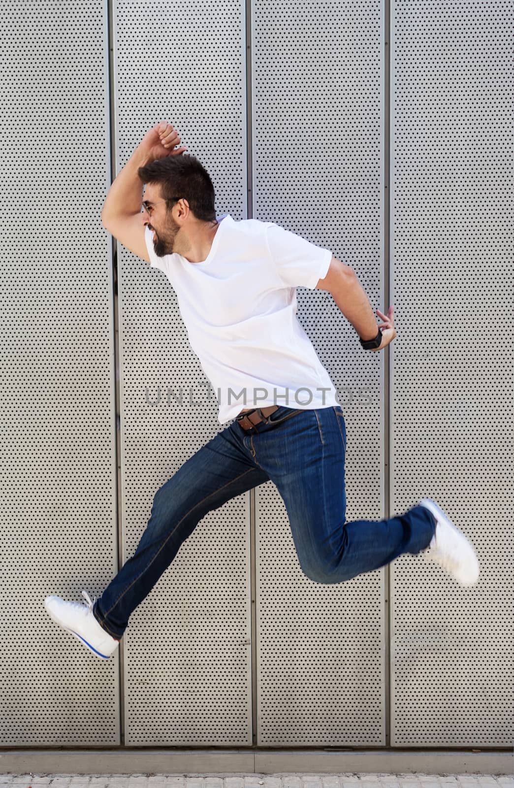 Bearded man with sunglasses jumping against metallic wall by raferto1973