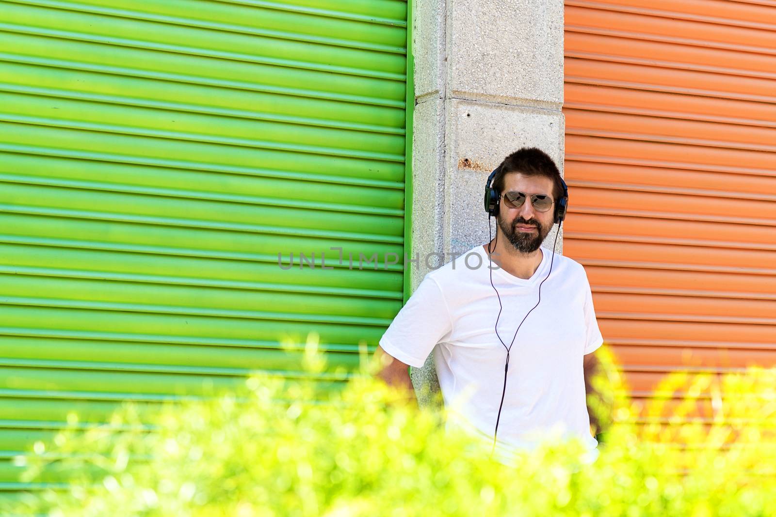 Cool trendy funny beard guy in headphones listening music on colored background.